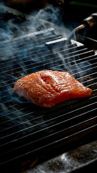 Delicious salmon fillet being grilled to perfection with aromatic smoke.