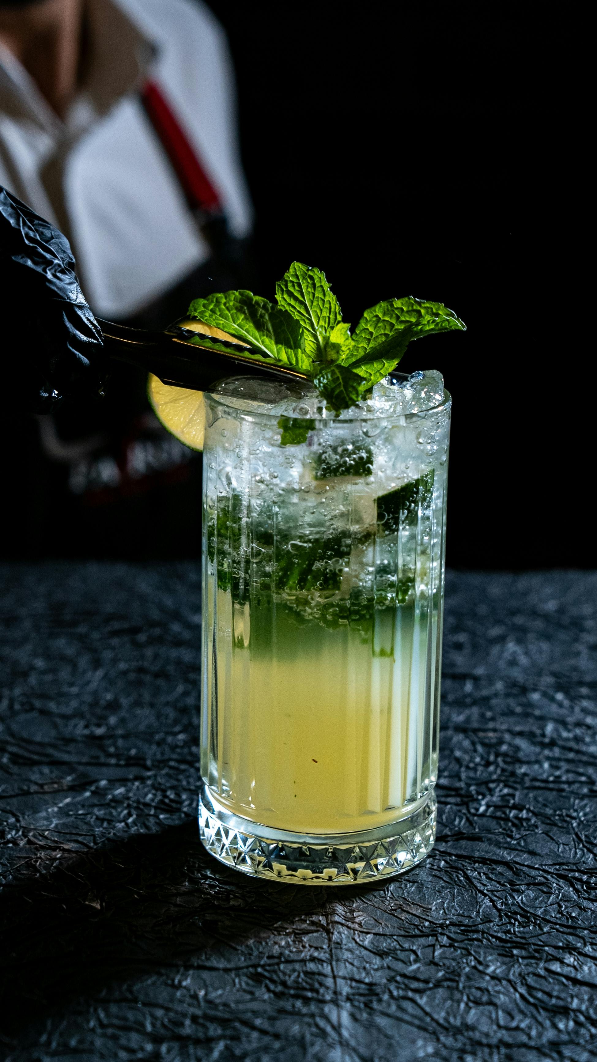 Bezpłatne Zbliżenie koktajlu mojito udekorowanego świeżą miętą na teksturowanej powierzchni. Zdjęcie z galerii