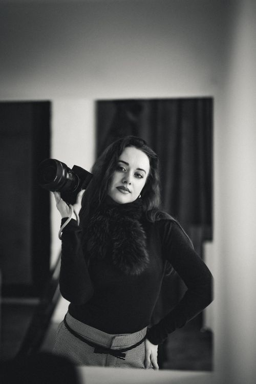 Free A black and white portrait of an elegant woman posing with a camera indoors. Stock Photo
