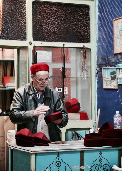 Free A craftsman in Tunisia carefully making traditional red hats inside a vintage shop. Stock Photo