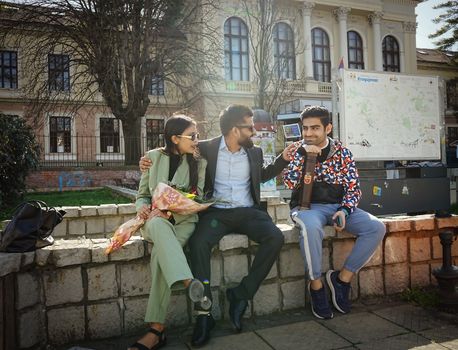 Three friends enjoying a sunny day outdoors at Kragujevac, Serbia, sharing a laugh and relaxing.