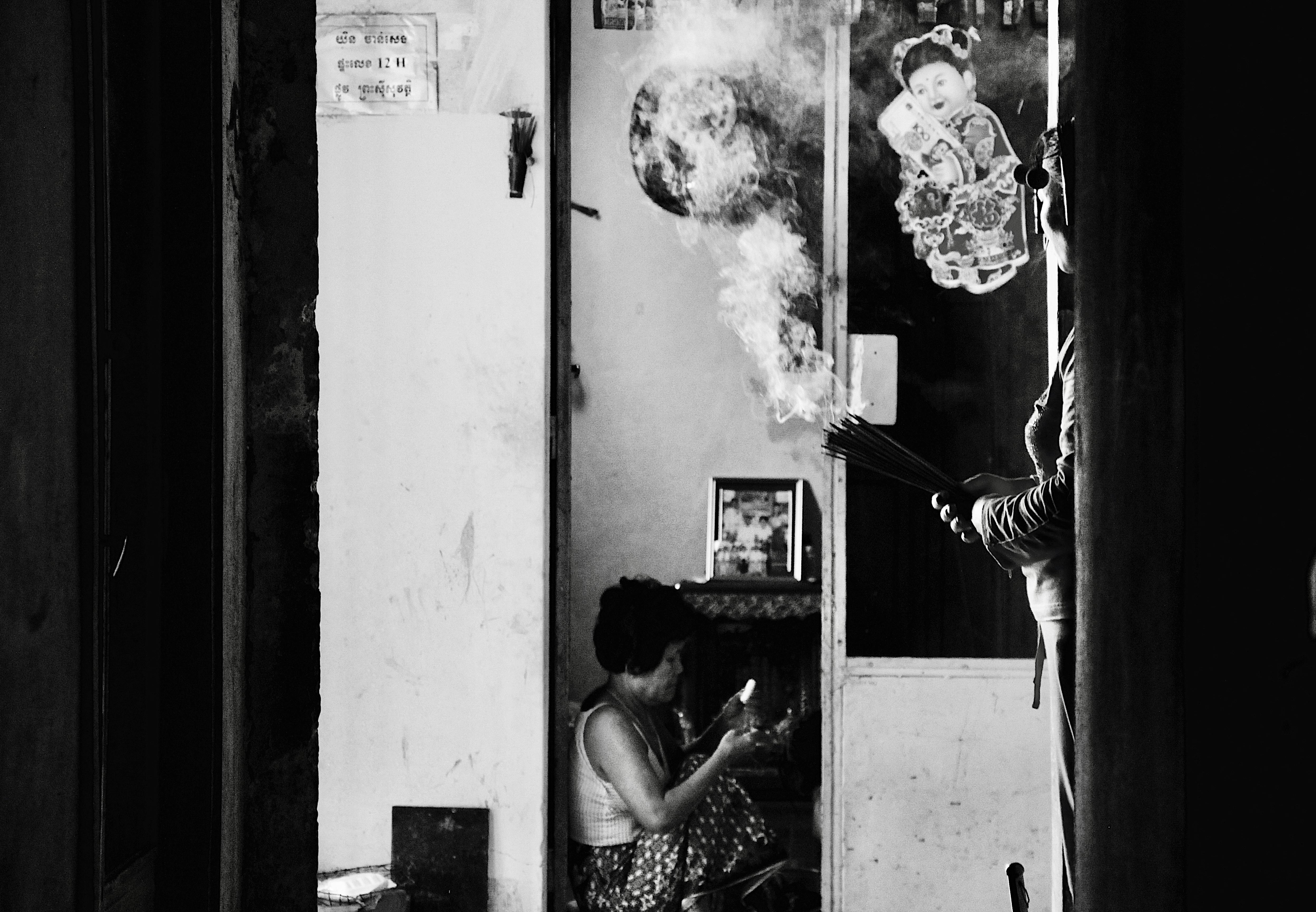 Безкоштовне Чорно-біла сцена, що зображує традиційний камбоджійський ритуал палення ладаном у приміщенні. стокове фото