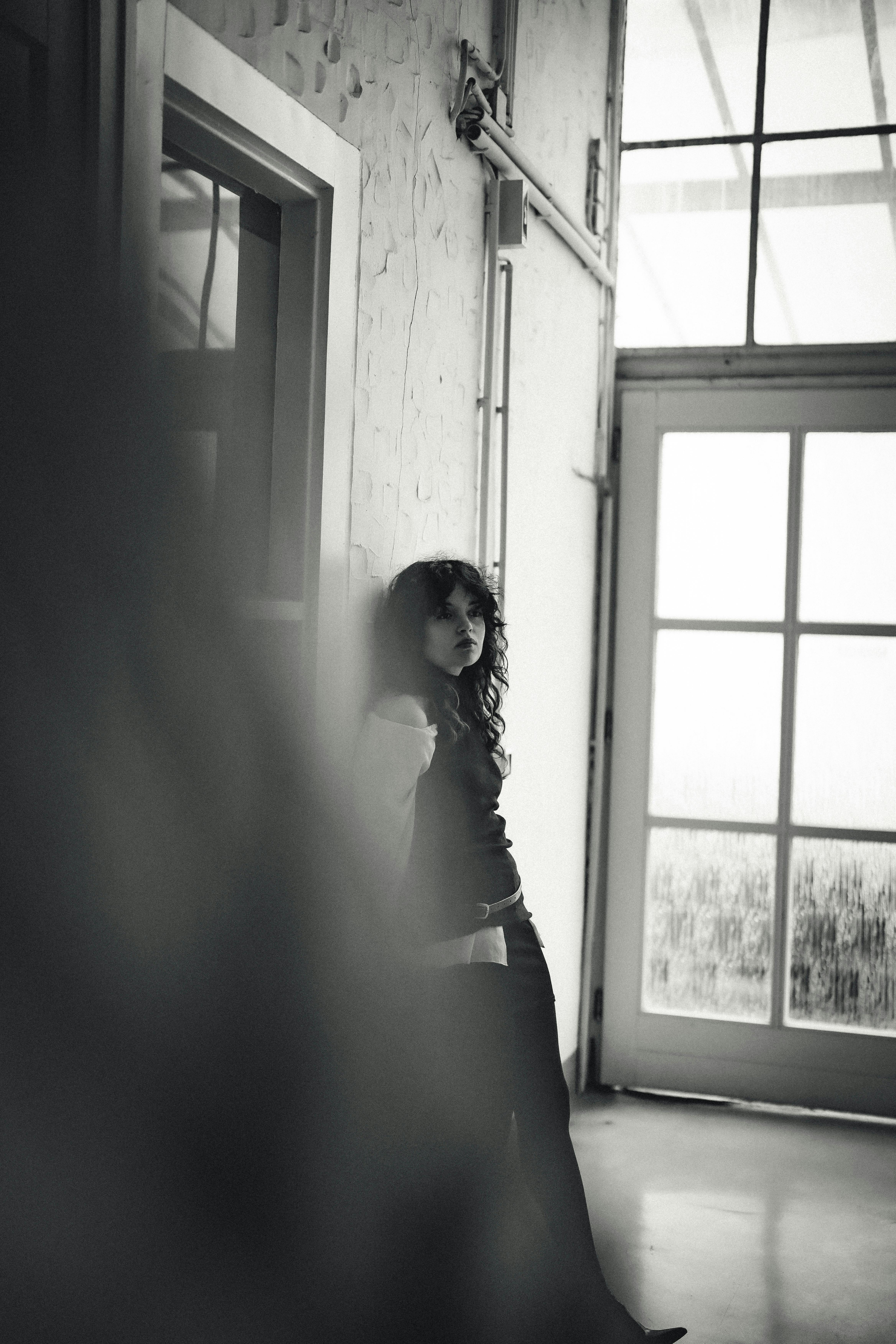 bezplatná Černobílý portrét ženy opřené o zeď uvnitř, Düsseldorf. Základová fotografie