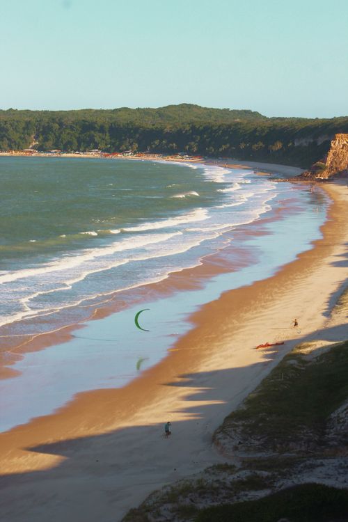 Free Aerial view of a beach with kite surfing at sunset, calm ocean waves, and sandy shores. Stock Photo