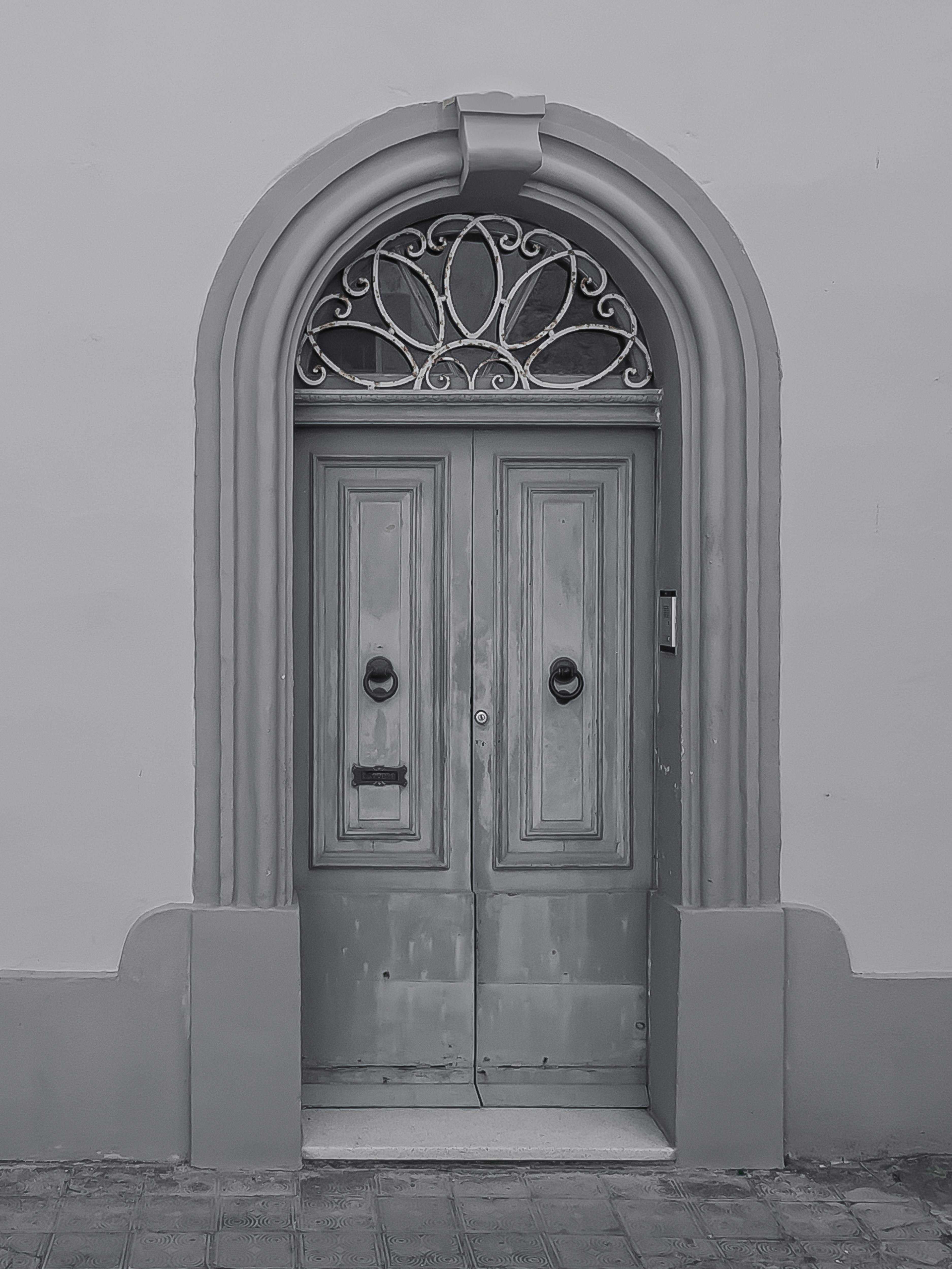 ฟรี ภาพถ่ายขาวดำของประตูไม้โค้งแบบคลาสสิกที่มีงานโลหะประณีต แสดงถึงเสน่ห์แบบวินเทจ คลังภาพถ่าย