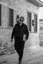 Stylish Man Walking By Stone Wall Outdoors