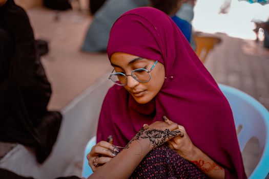A skilled henna artist creating intricate designs on a client's hand in Mogadishu, Somalia.