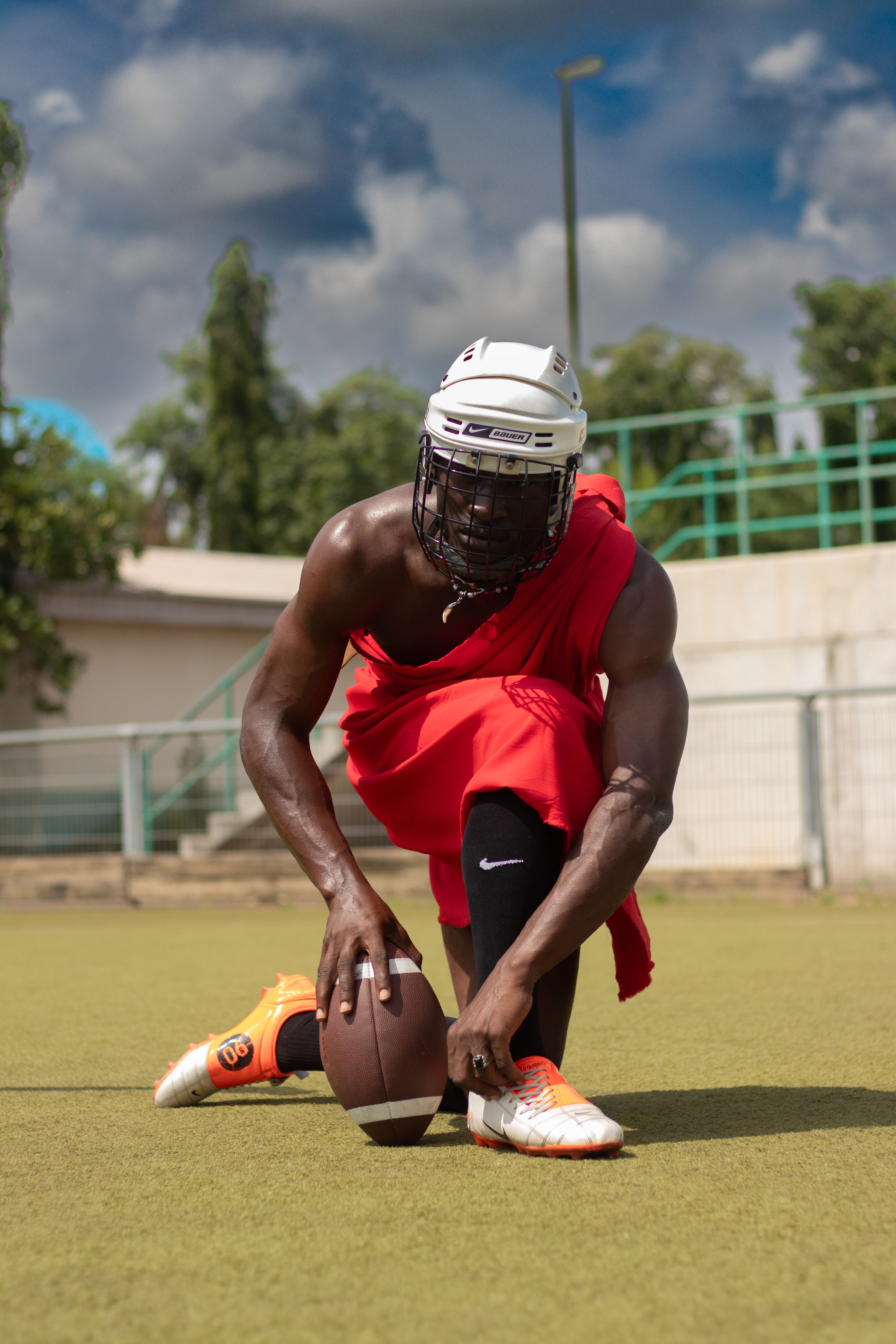 Football player in helmet and red attire poised on a sports field in Abuja, Nigeria.