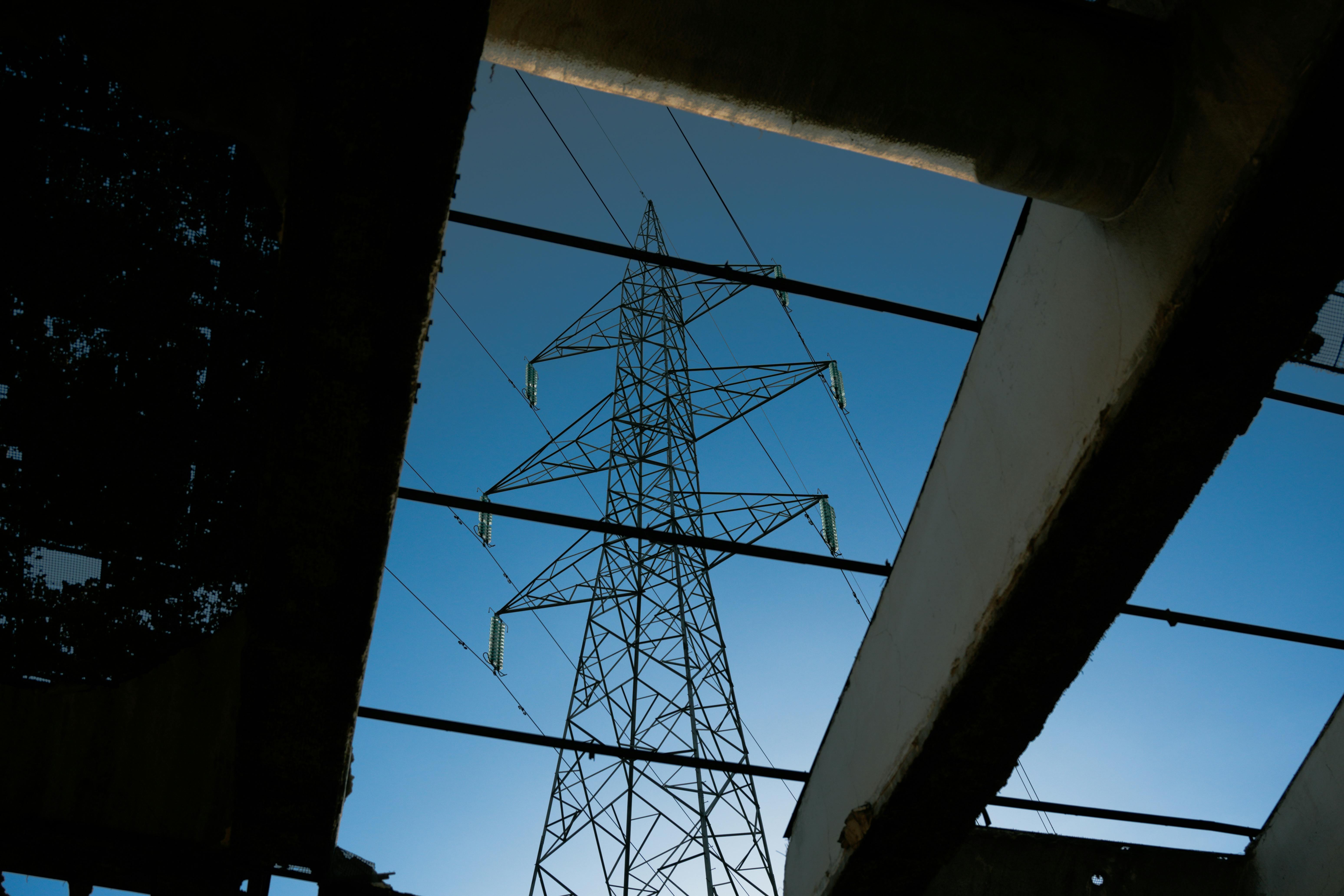 bezplatná Elektrická věž orámovaná průmyslovými ruinami proti modré obloze. Základová fotografie