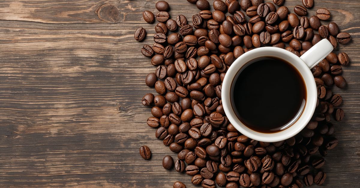 Aerial view of a coffee cup surrounded by roasted beans on wood. - Evidence evidence guide for caffeine exercise performance randomized trial