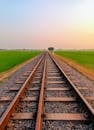 Railroad Tracks Amidst Lush Fields at Sunset