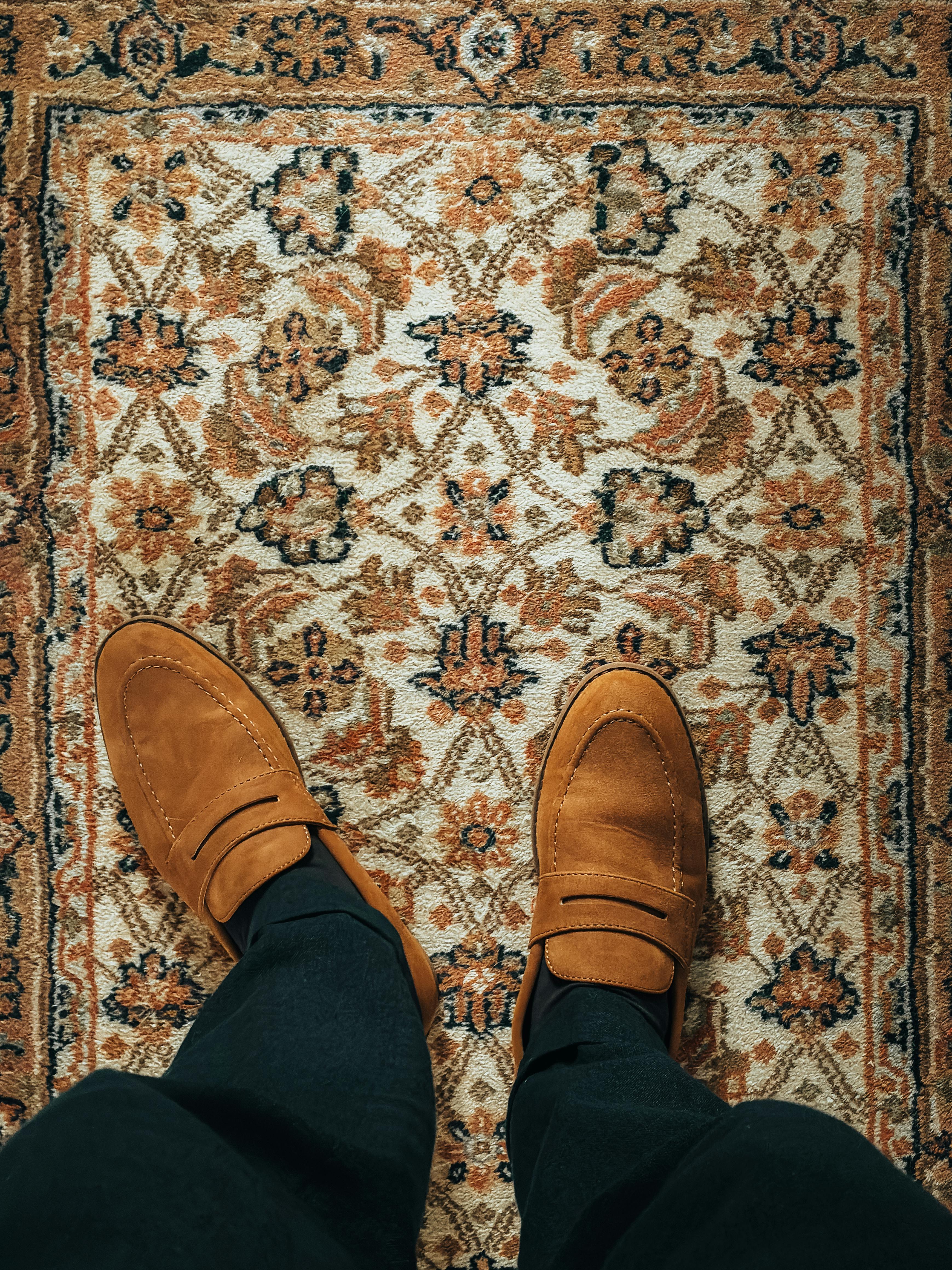 Miễn phí Đôi giày lười trên tấm thảm trang trí cầu kỳ, làm nổi bật những họa tiết phong phú và màu sắc ấm áp. Ảnh lưu trữ