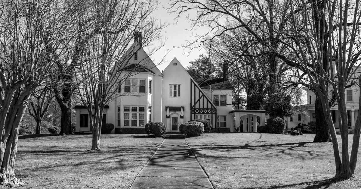 Elegant Tudor-style house surrounded by trees in Hampton, Virginia on a sunny day.