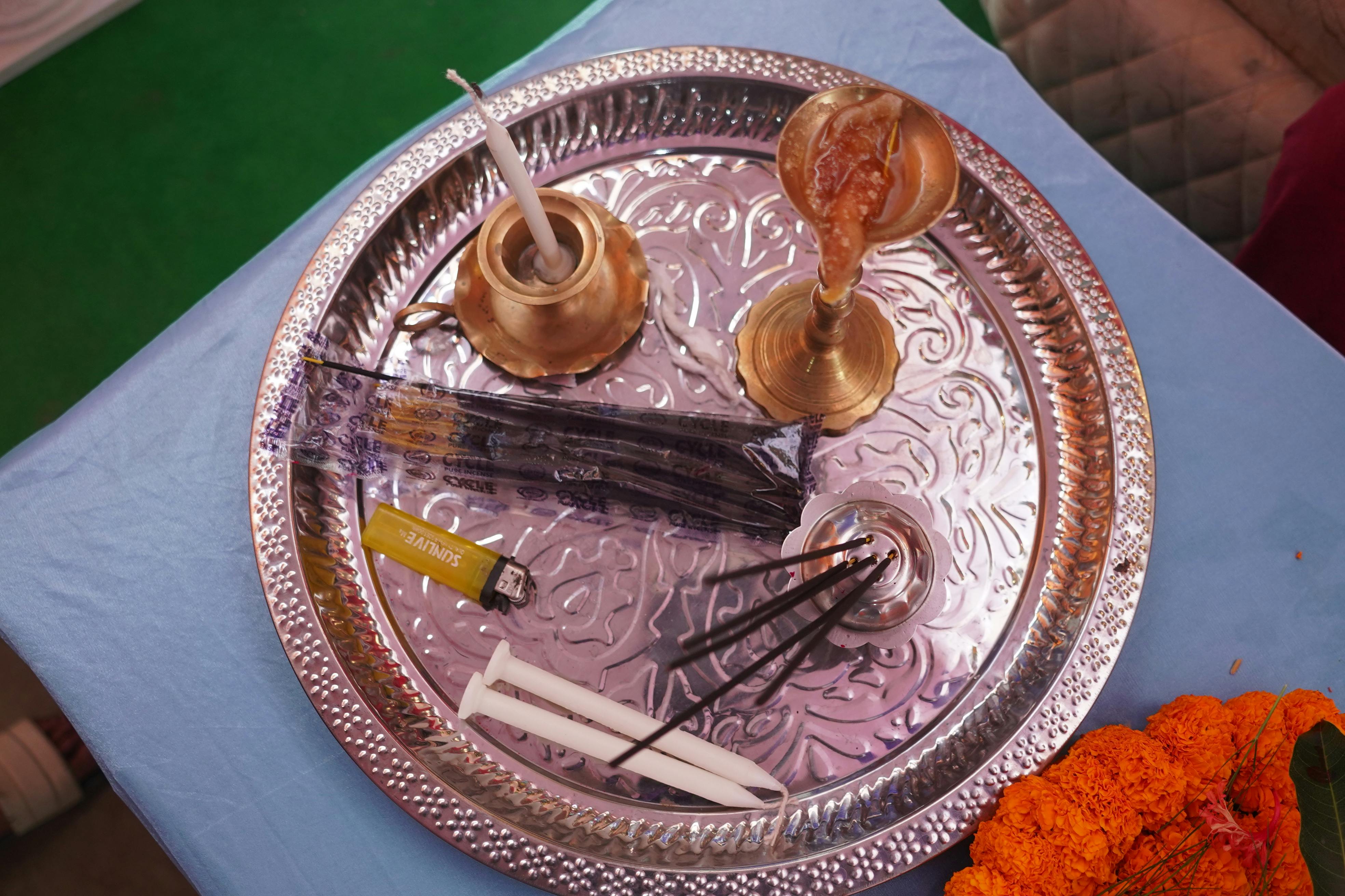 Gratis En sølvbakke indeholder traditionelle rituelle genstande, herunder røgelsespinde, morgenfrueblomster og messingredskaber. Lagerfoto