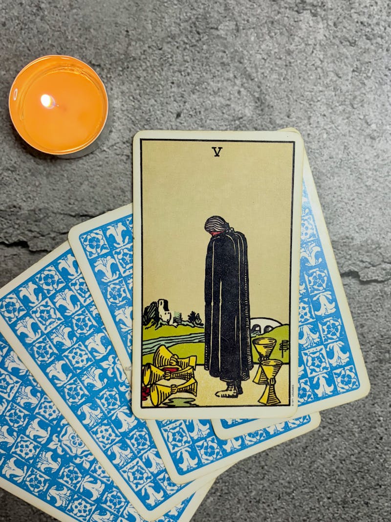 Tarot cards spread on a surface with a lit candle, warm and gentle atmosphere