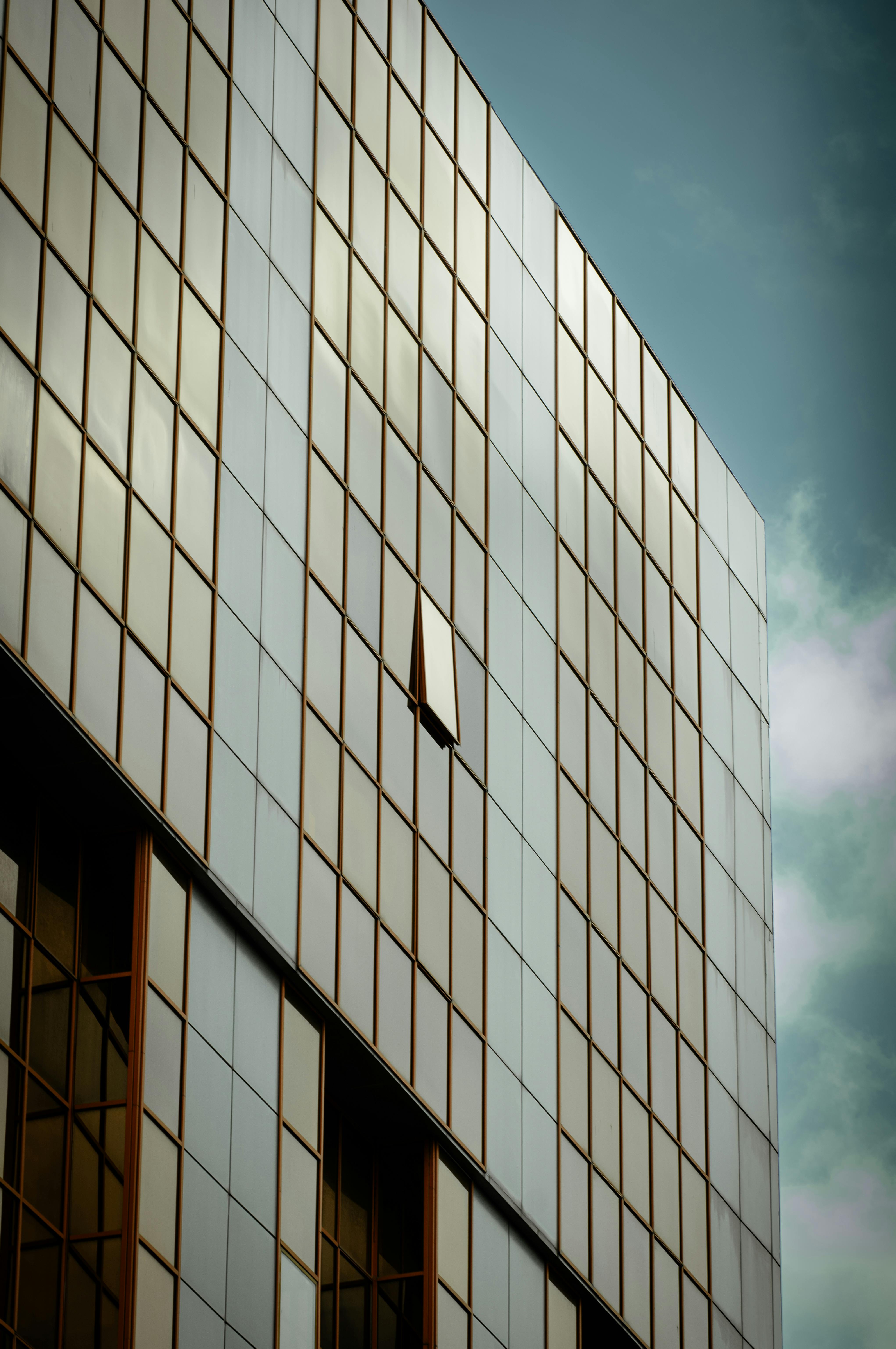 ingyenes Magas épület üveghomlokzata nyitott ablakkal felhős ég alatt. Stockfotó