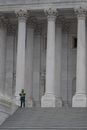 A Police Officer Standing Near White Concrete Pillars Of A Building
