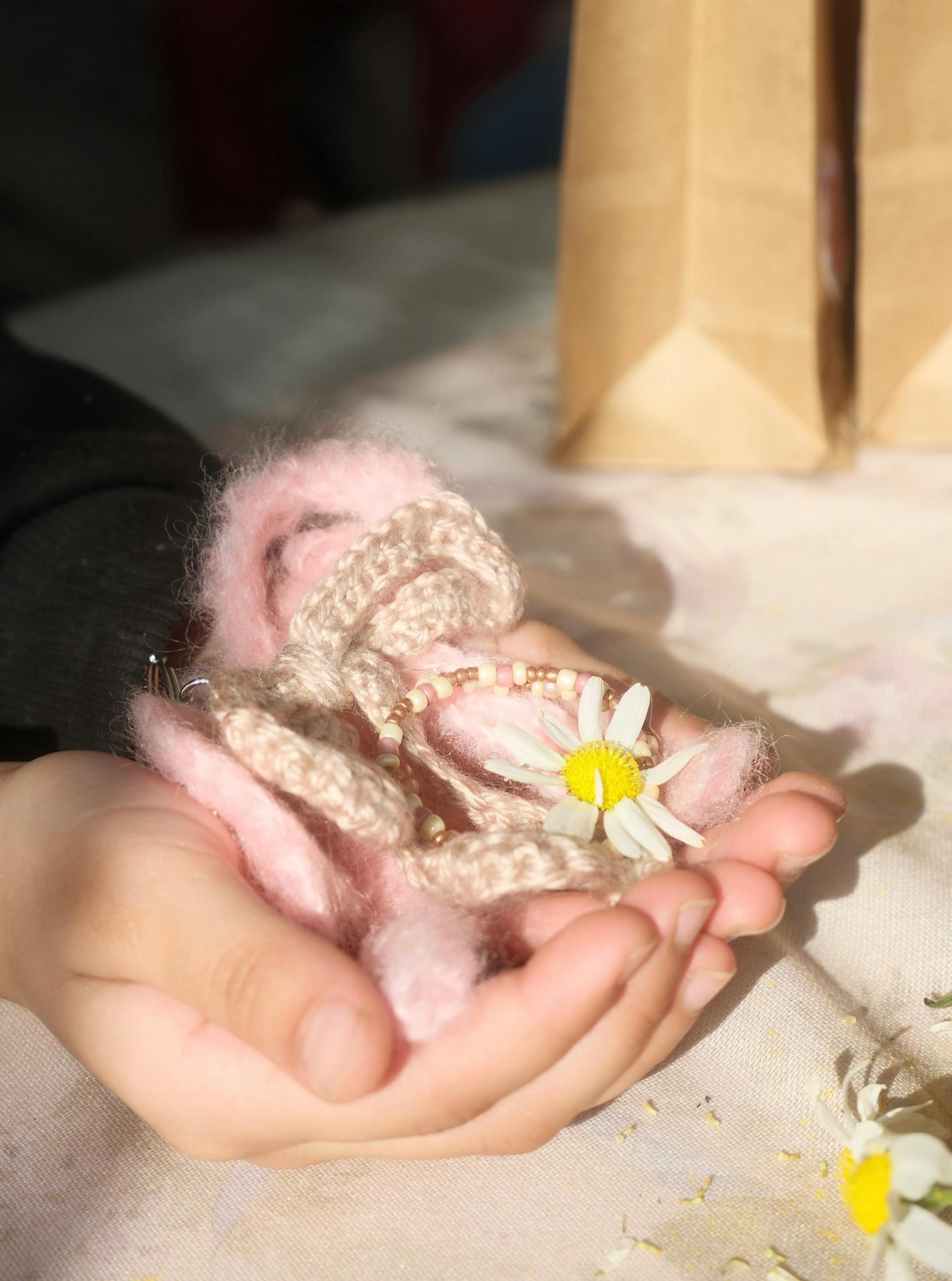 免費 特寫鏡頭：雙手握著繡有雛菊的毛線，體現出溫暖與創造力。 圖庫相片