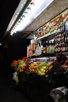 Vibrant display of fresh fruits and beverages at a street stall in Rome by night.