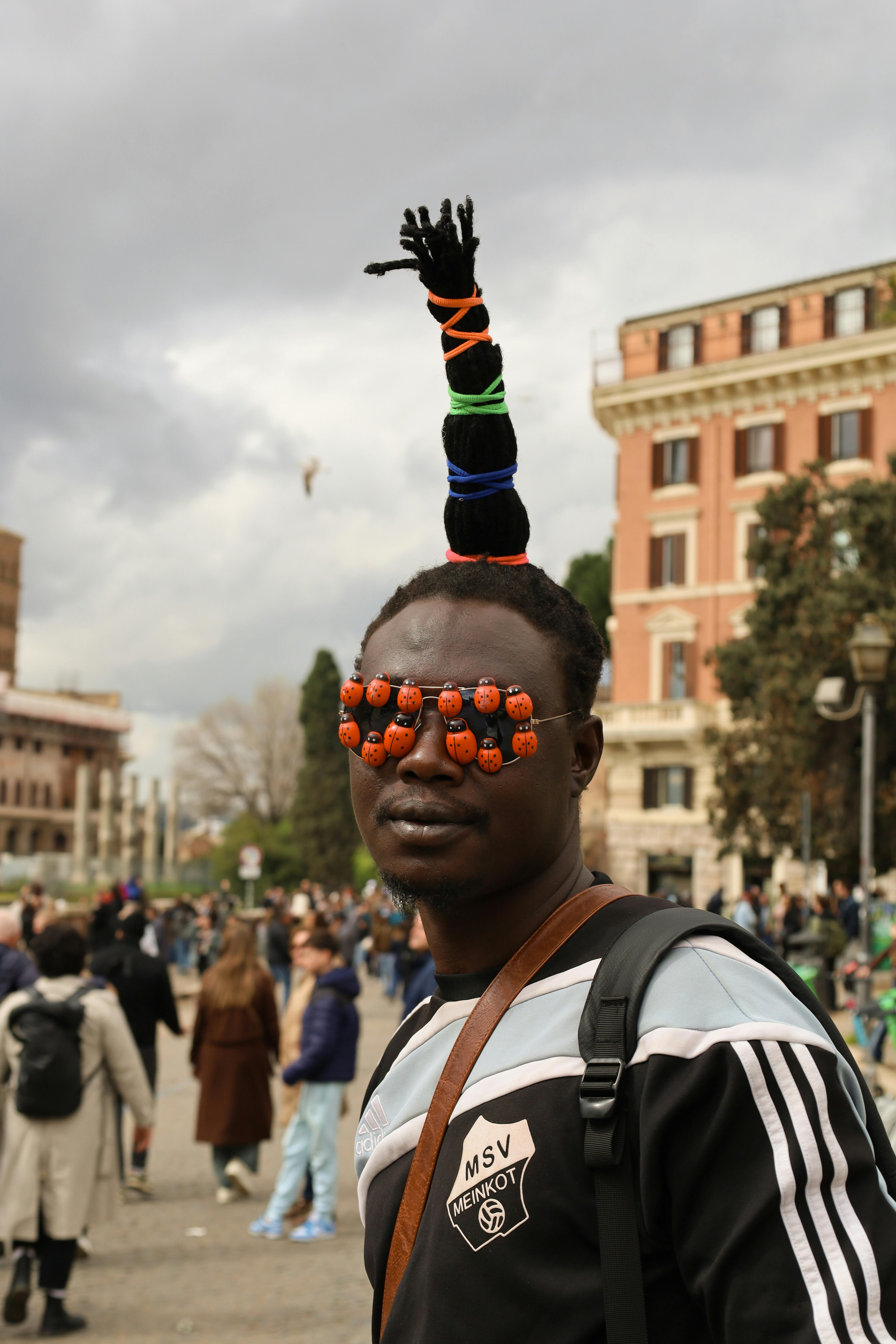 Безкоштовне Вражаюча вулична сцена в Римі, на якій зображений чоловік в унікальному головному уборі та окулярах. стокове фото