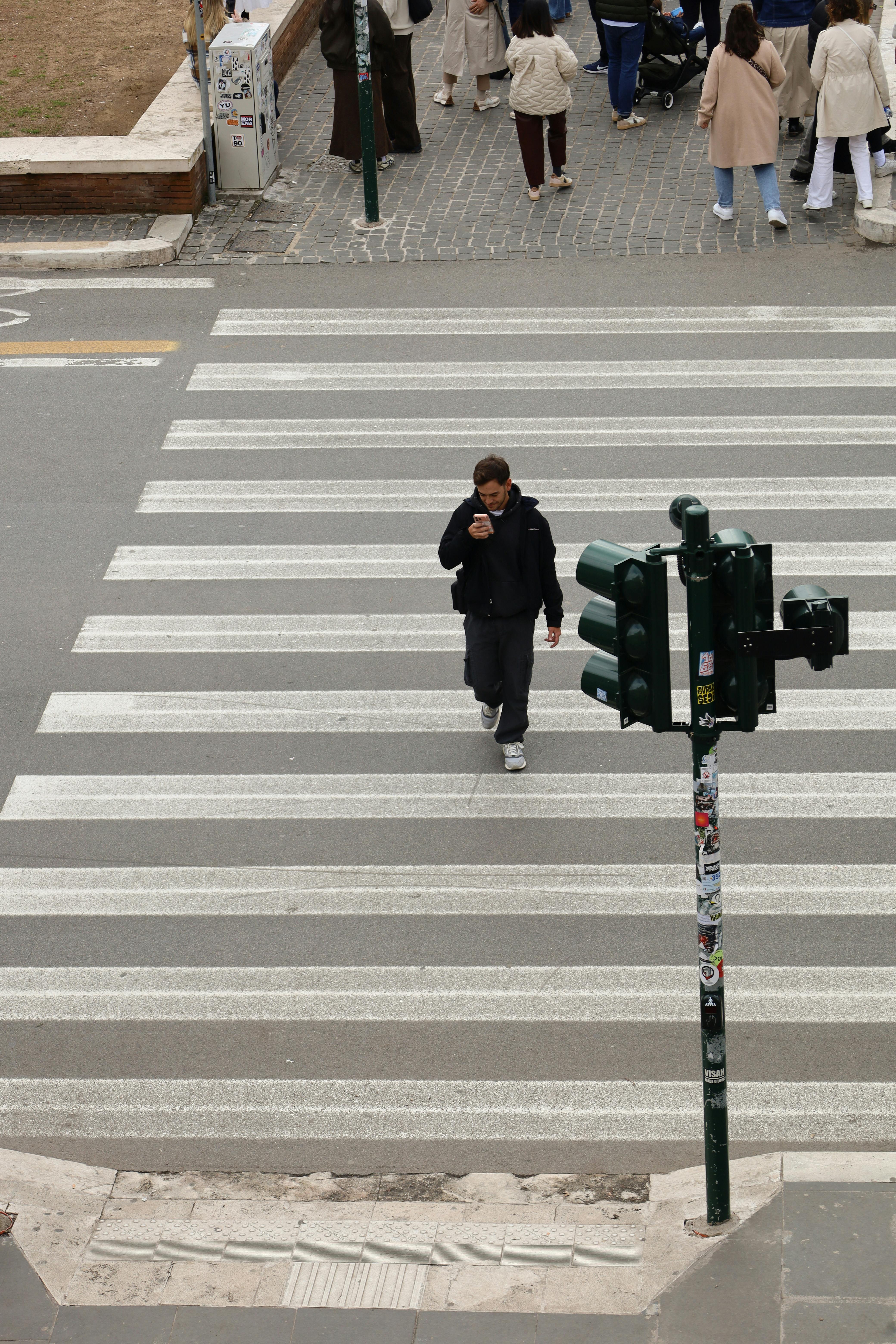 ฟรี ชายคนหนึ่งเดินข้ามทางม้าลายในกรุงโรม ภาพนี้สะท้อนให้เห็นถึงแก่นแท้ของชีวิตในเมือง คลังภาพถ่าย