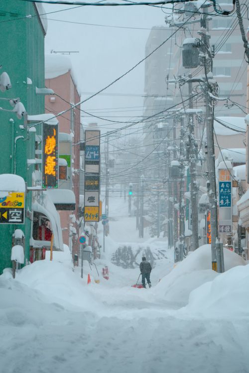 Free A person walks through a snow-covered street in Sapporo, Hokkaido, during winter. Stock Photo