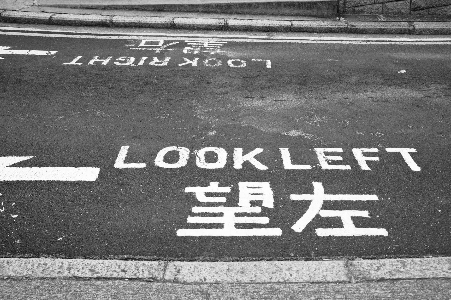 Street warning sign in Hong Kong advising pedestrians to look left for safety.