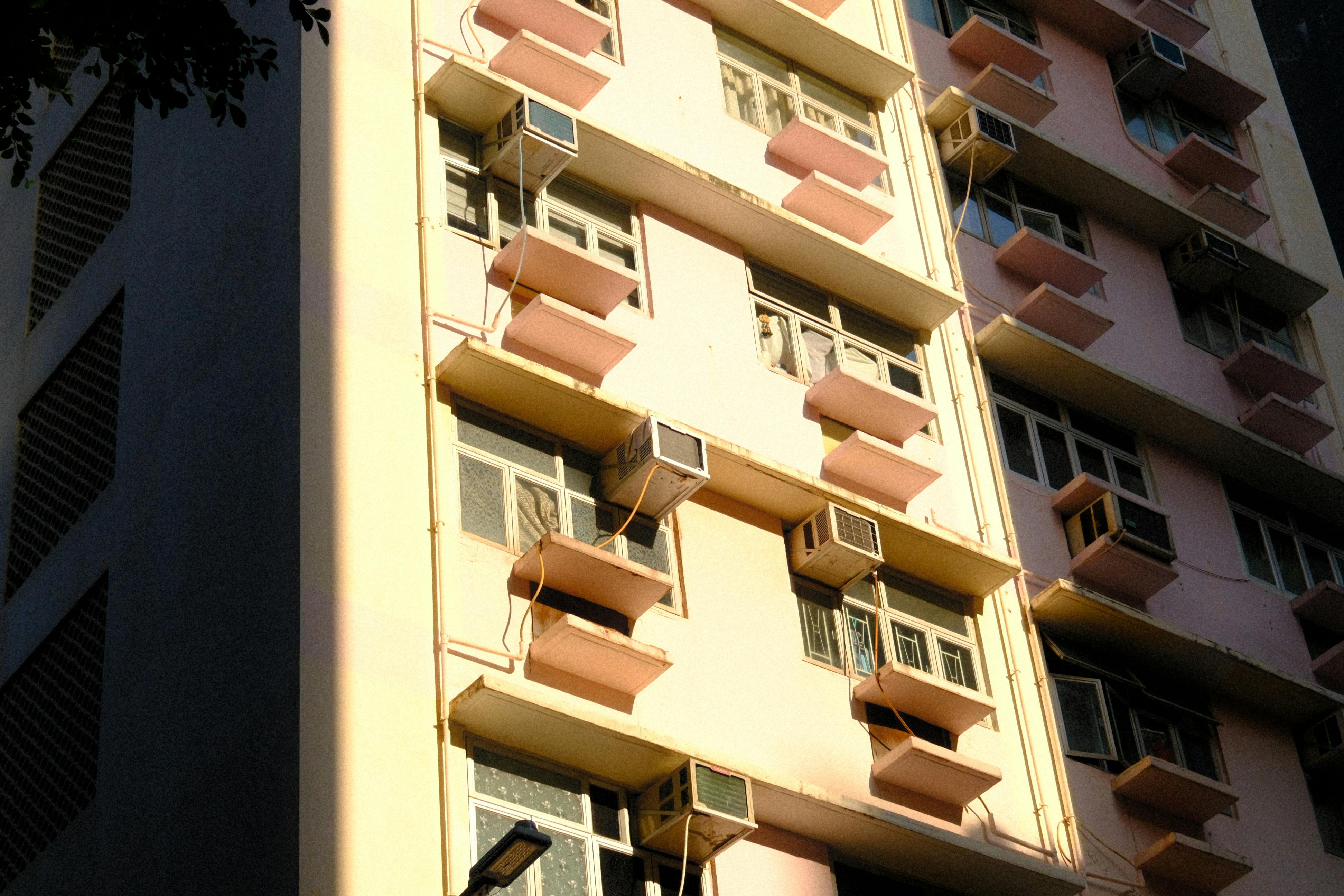 bezplatná Sluncem zalitá fasáda hongkongského bytu s klimatizací a pastelovými barvami. Základová fotografie