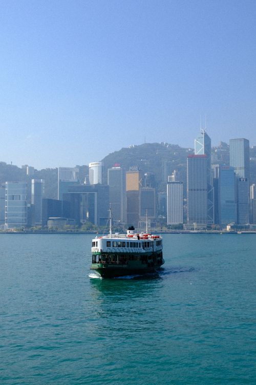 Free The famous Star Ferry crosses the harbor with Hong Kong's skyline in the background. Stock Photo