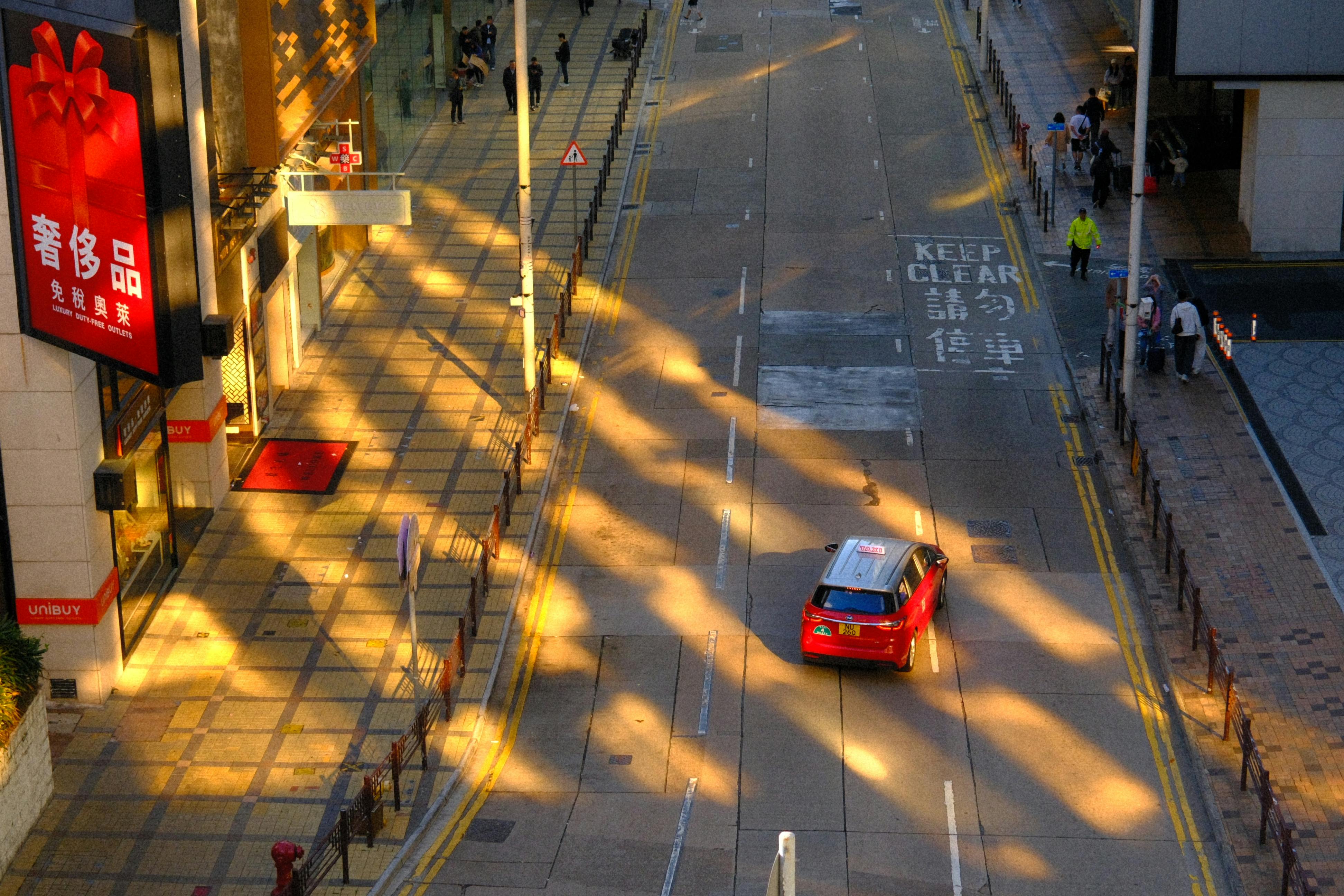 Gratis Luftfoto af en klart oplyst bygade i Hong Kong med en rød taxa og fodgængere. Lagerfoto