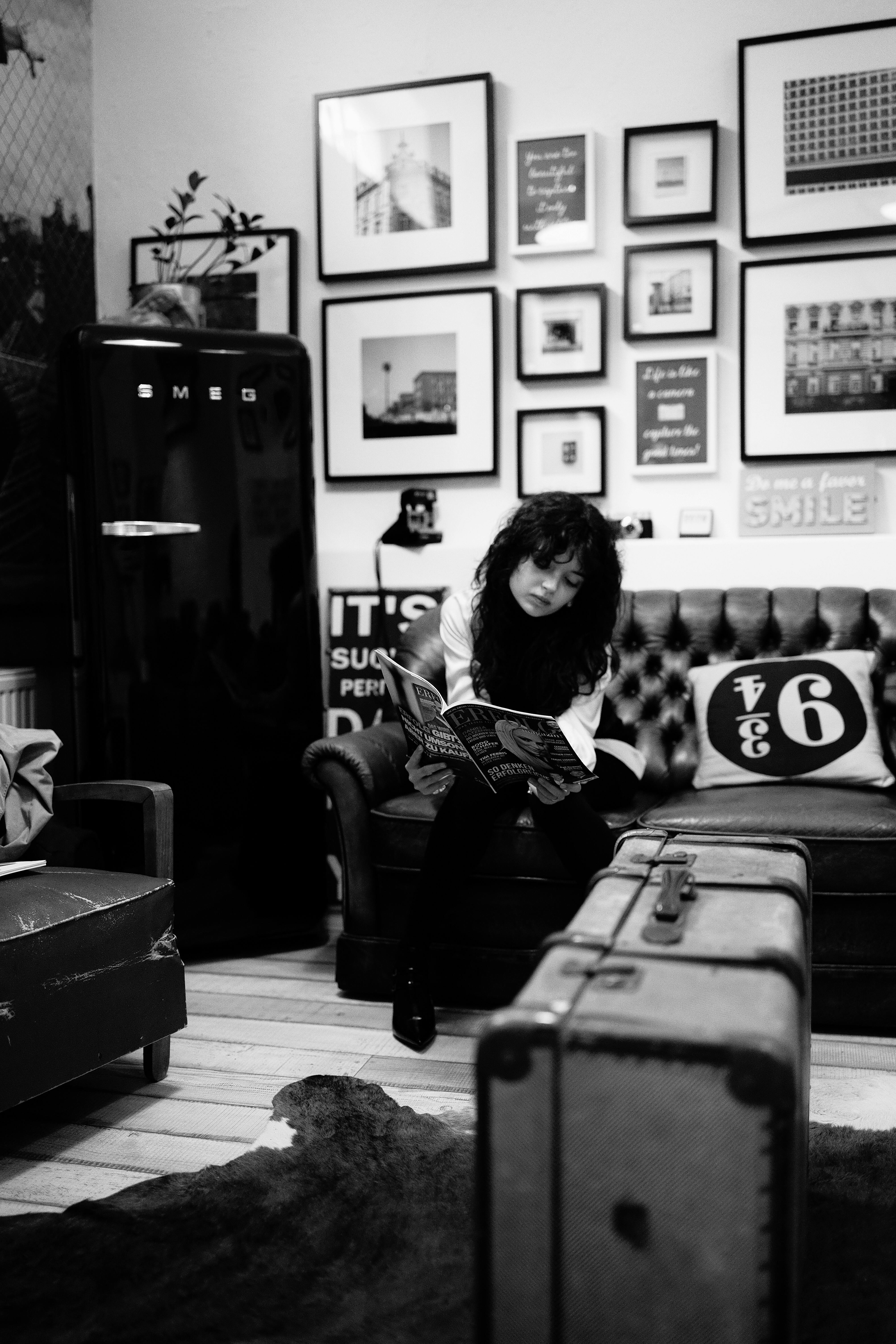 Miễn phí Không gian nội thất ấm cúng với một người đang đọc sách giữa khung cảnh trang trí cổ điển, chiếc vali kiểu retro và những bức tranh được đóng khung. Ảnh lưu trữ