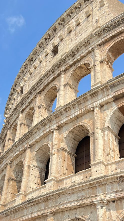 Free Captivating side view of the iconic Roman Colosseum under a clear blue sky, showcasing its ancient architecture. Stock Photo