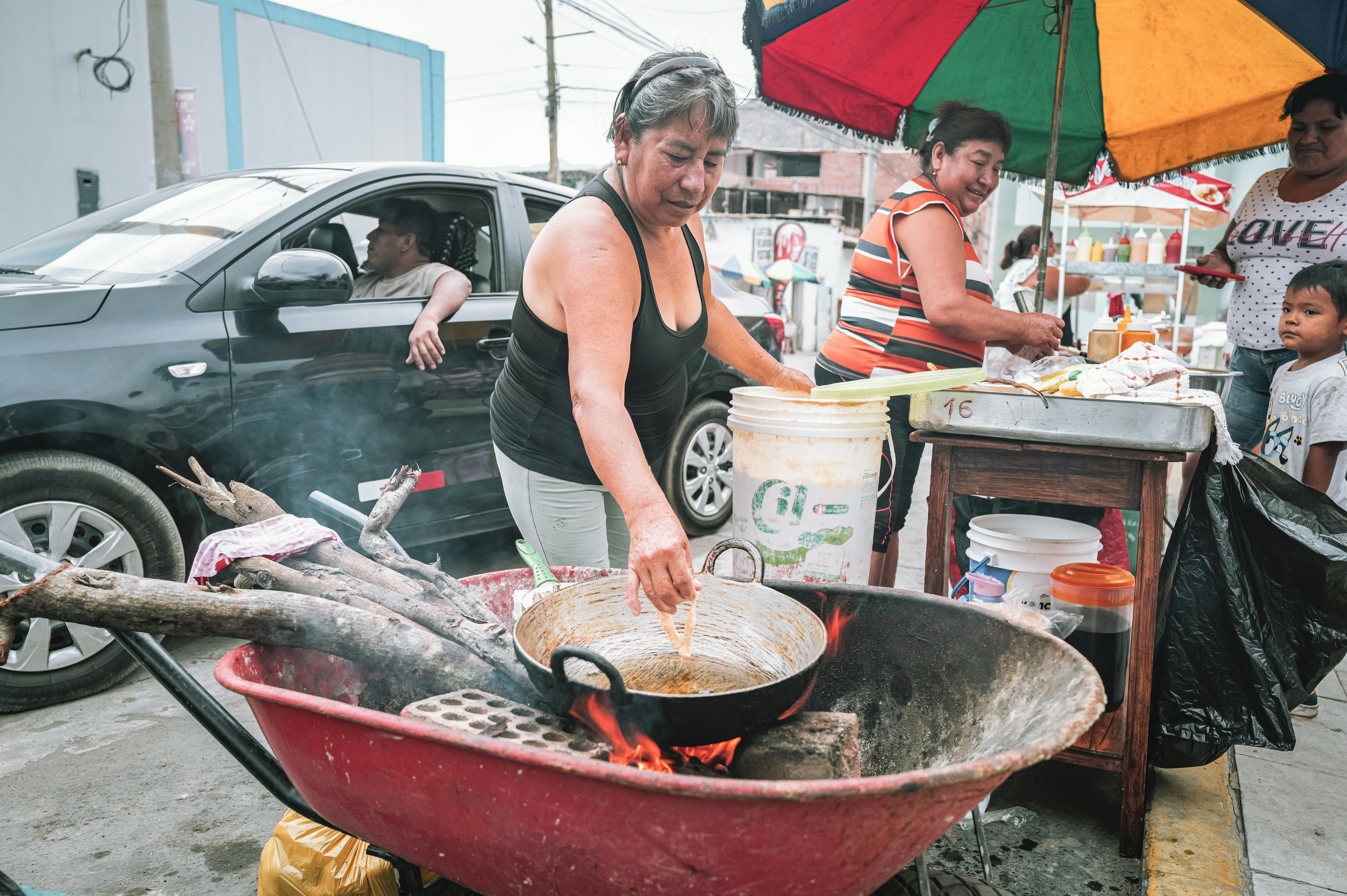 Street food vendor in Ho Central Market frying tilapia with smoke rising