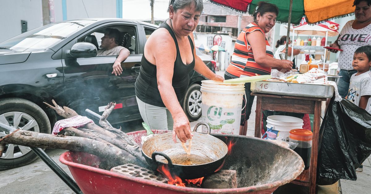 Street food vendor in Ho Central Market frying tilapia with smoke rising