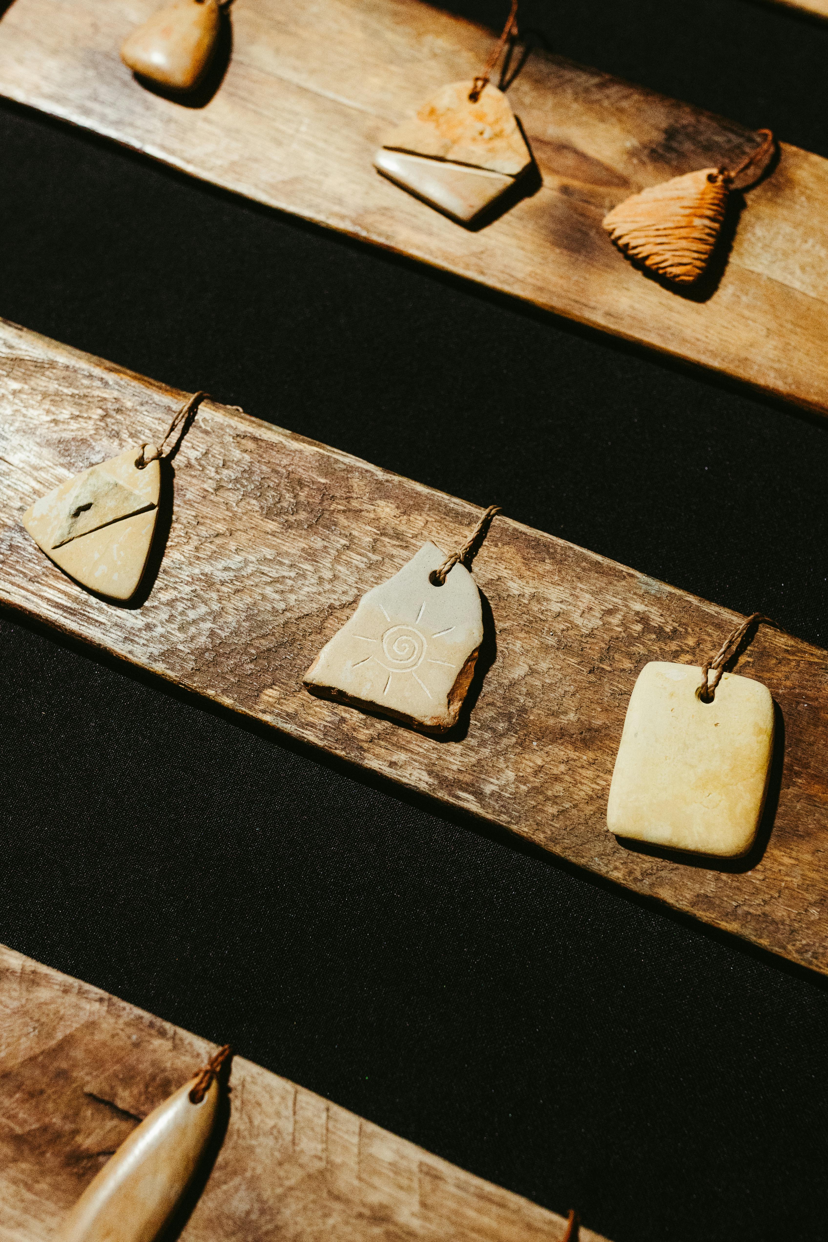 Безкоштовне Крупний план кам'яних підвісок ручної роботи, розташованих на сільському дерев'яному дисплеї. стокове фото