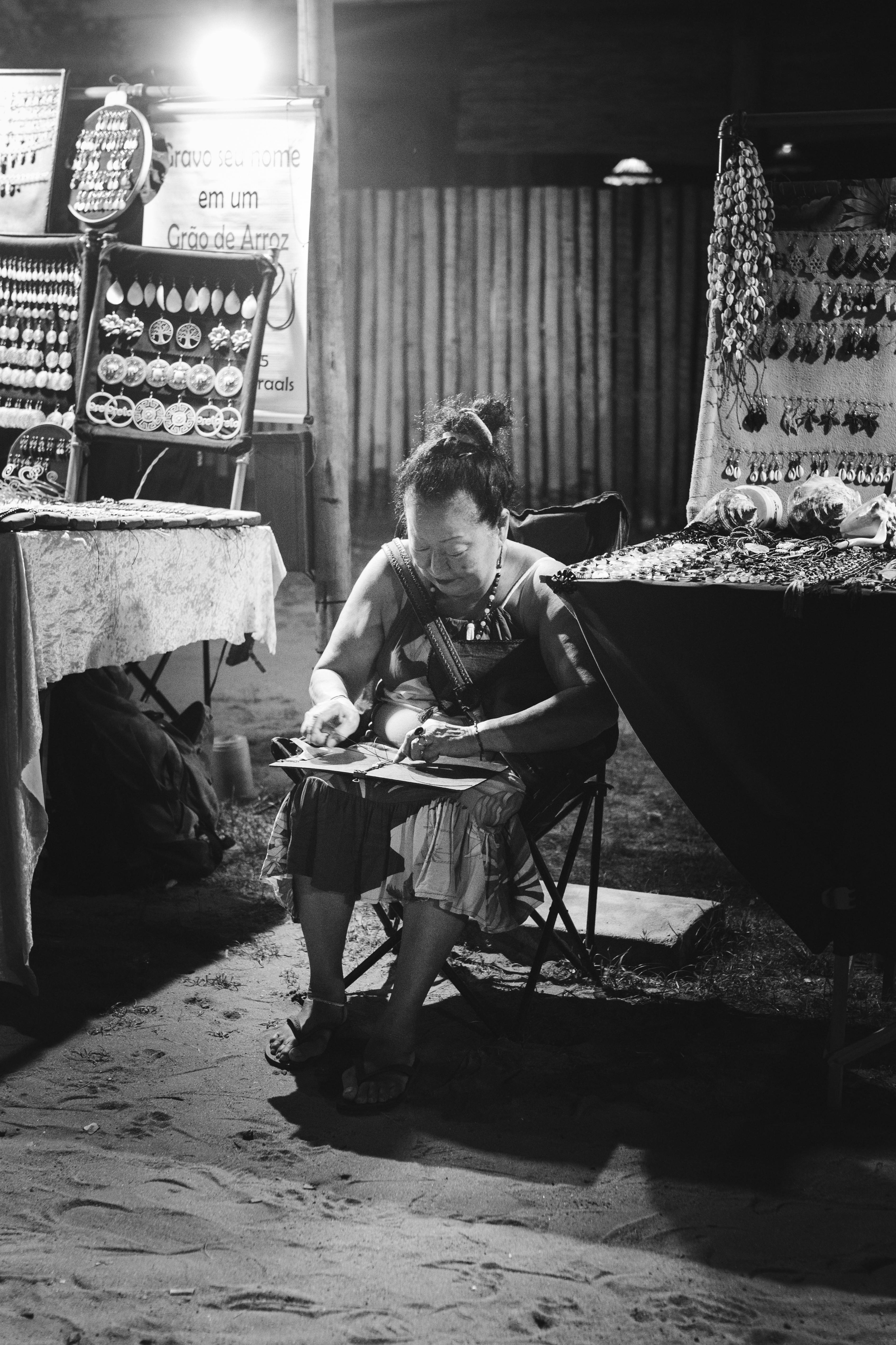 免費 一位工匠坐在夜市裡，在柔和的燈光下製作珠寶。 圖庫相片