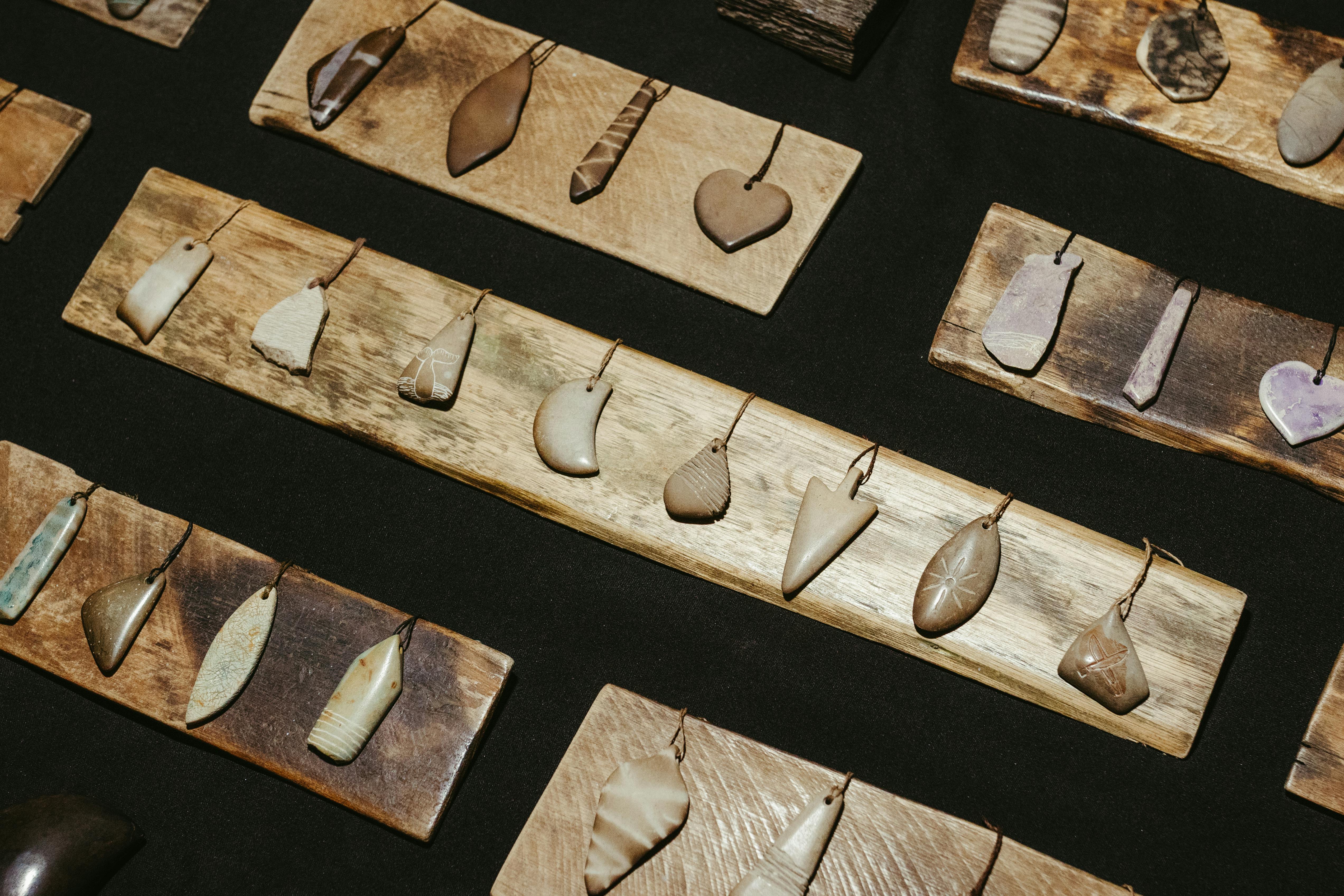 Zadarmo Kolekcia rustikálnych kamenných príveskov elegantne vystavených na drevených doskách, ktoré prezentujú remeselné spracovanie. Fotka z fotobanky