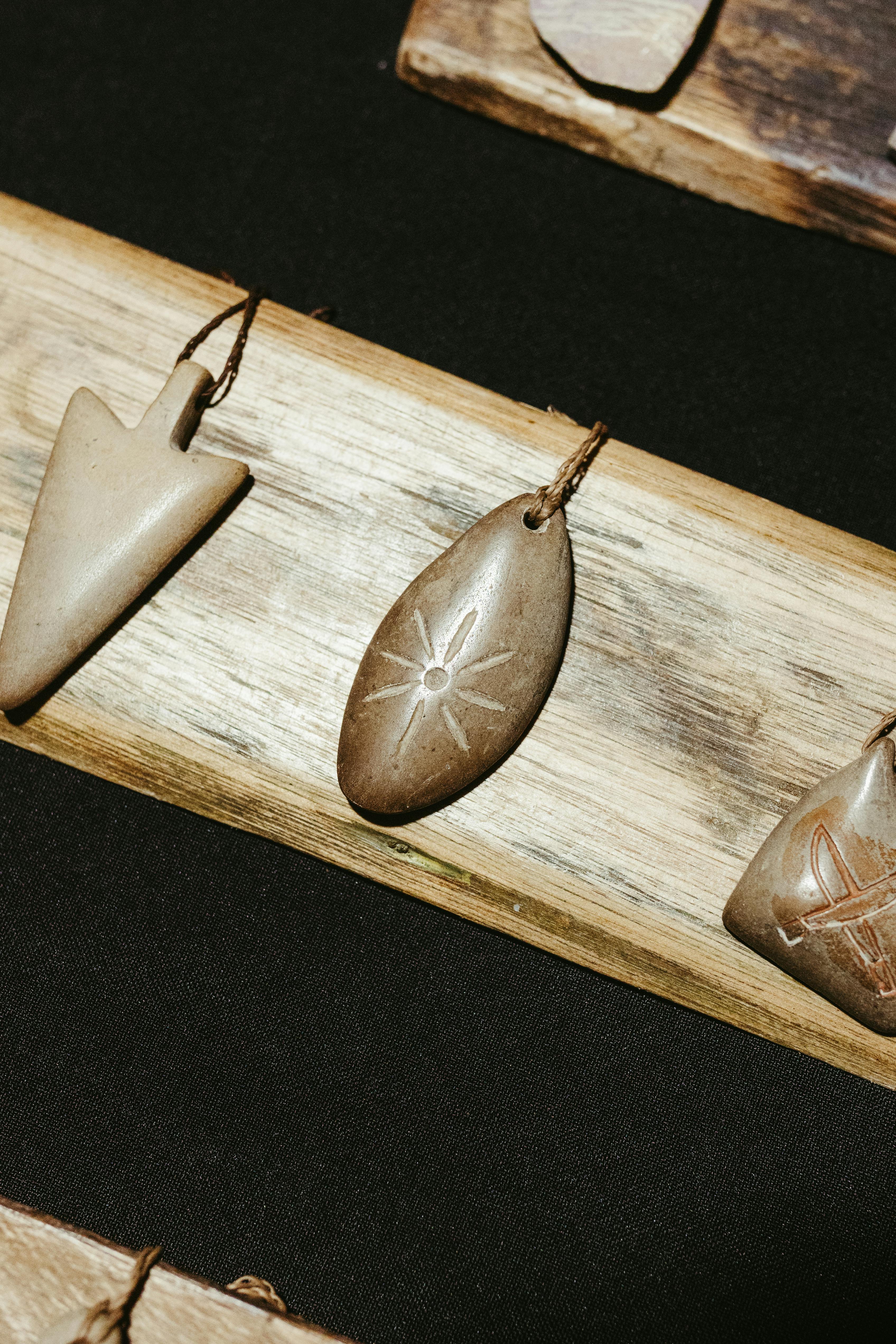 Miễn phí Hình ảnh cận cảnh những mũi tên và mặt dây chuyền bằng đá thô sơ trên một tấm ván gỗ, làm nổi bật kết cấu tự nhiên. Ảnh lưu trữ