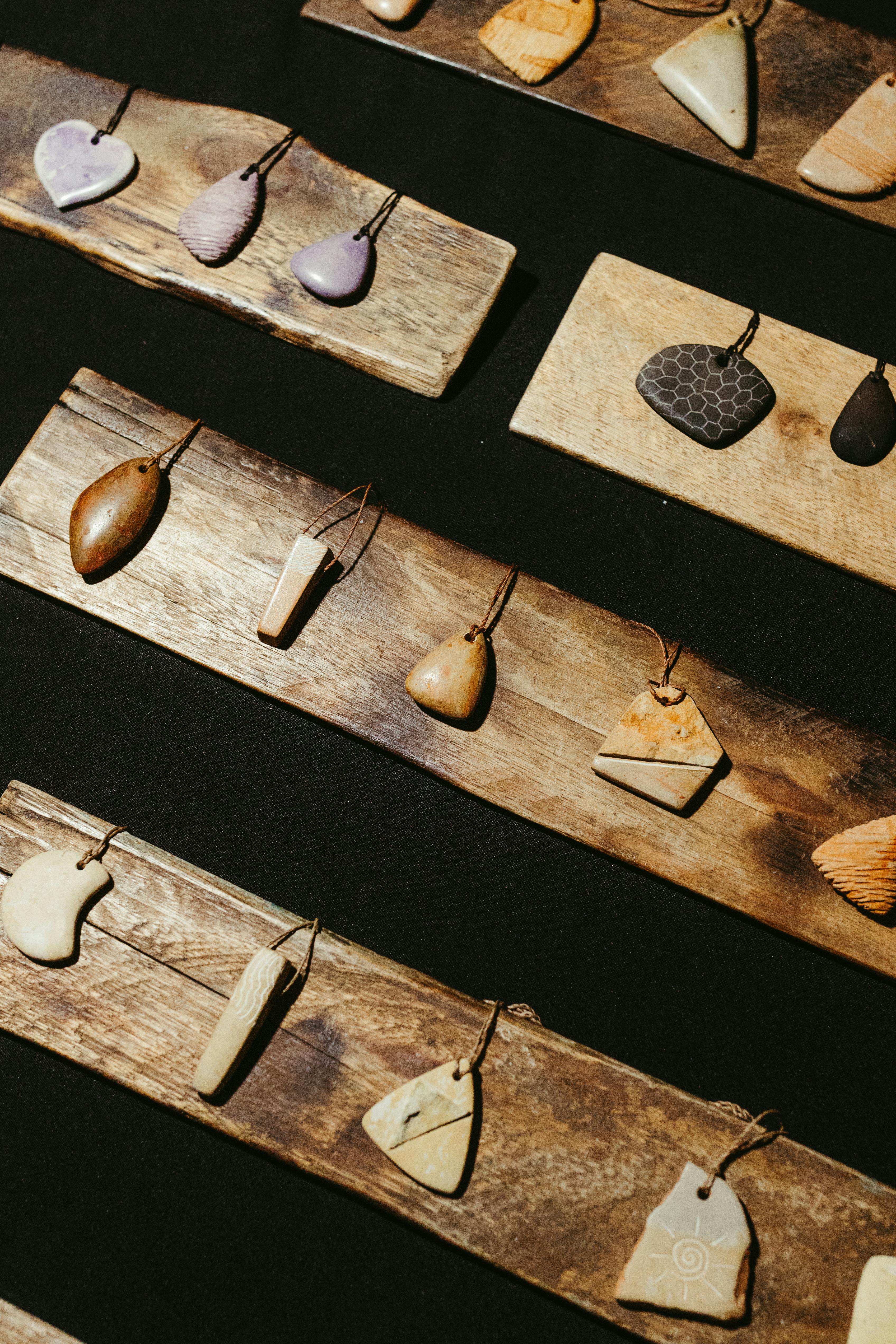 Zadarmo Remeselné kamenné prívesky vystavené na rustikálnych drevených doskách. Ideálne na remeselné trhy, prírodné šperky a ručne vyrábané návrhy. Fotka z fotobanky