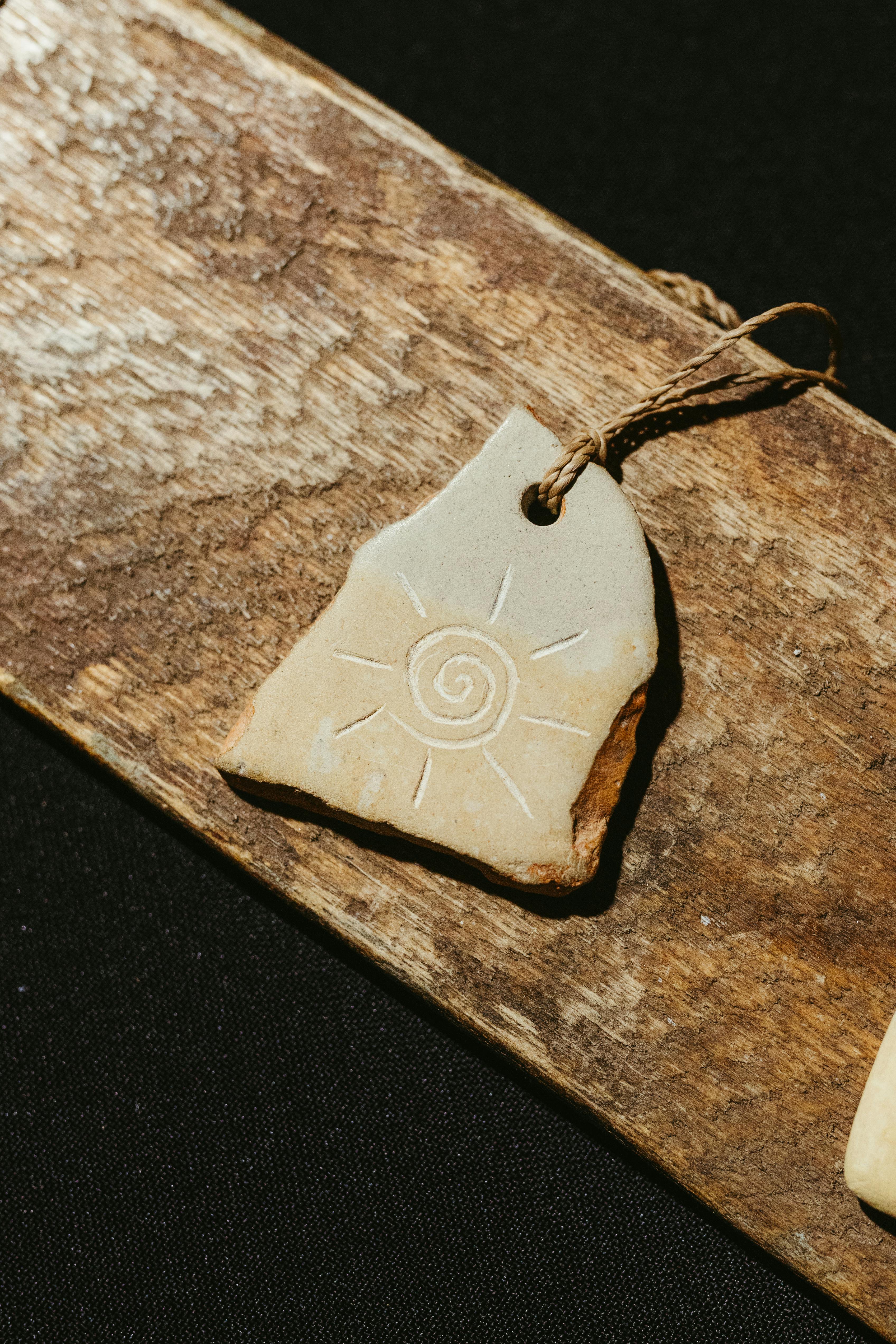 Zadarmo Ručne vyrobený hlinený prívesok so slnečným dizajnom na rustikálnom drevenom pozadí. Fotka z fotobanky