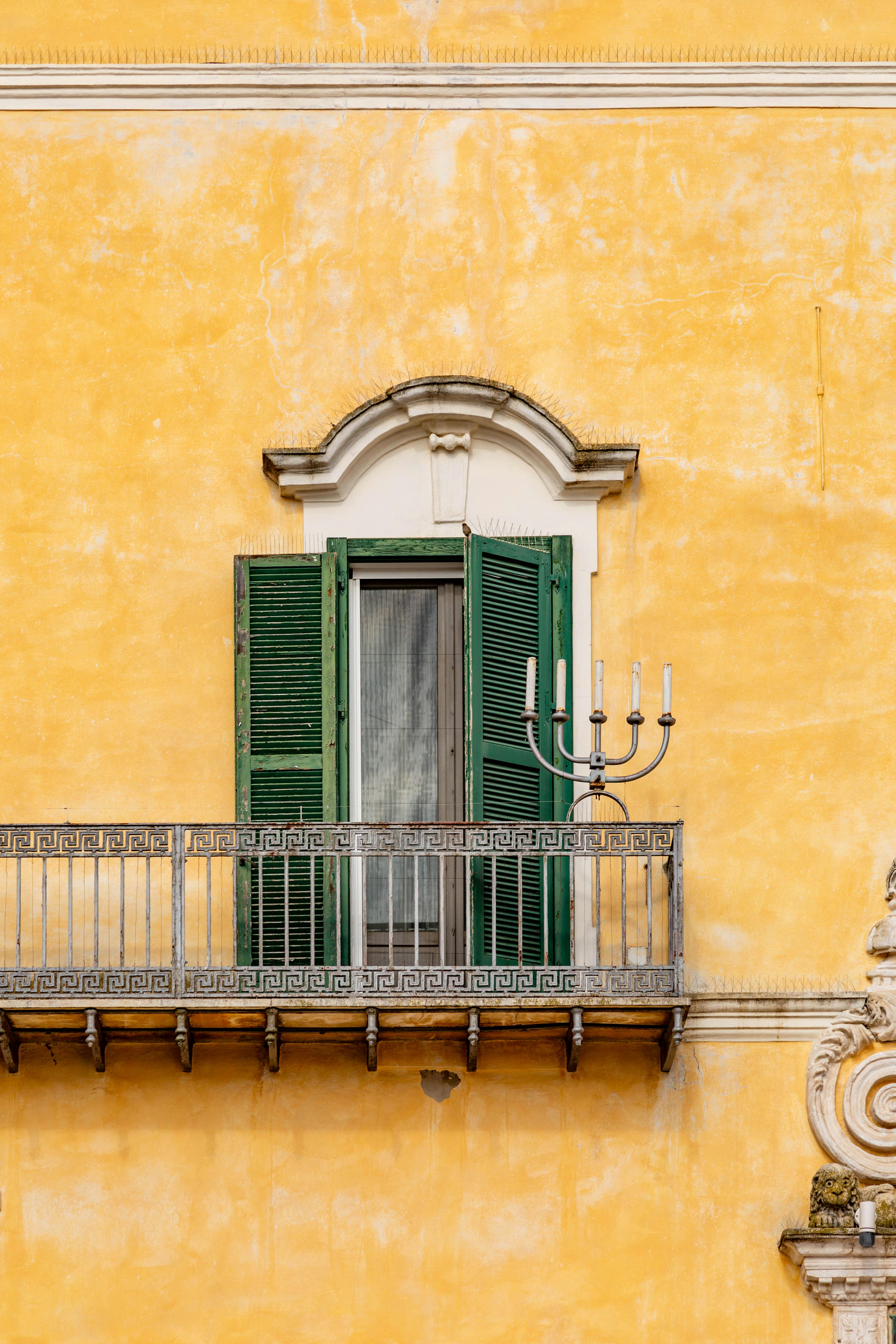 bezplatná Zářivá žlutá fasáda s klasickým zeleným balkonem s okenicemi v Bari v Apulii. Základová fotografie