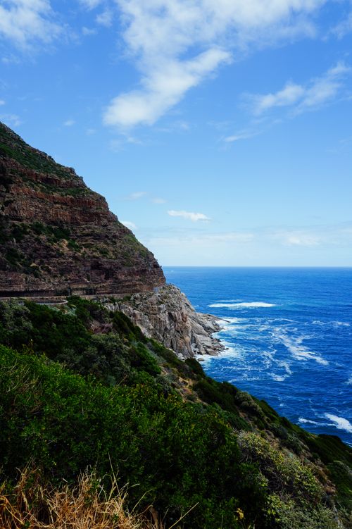 Free Breathtaking view of a rocky cliffside overlooking a vibrant ocean under a clear blue sky. Stock Photo