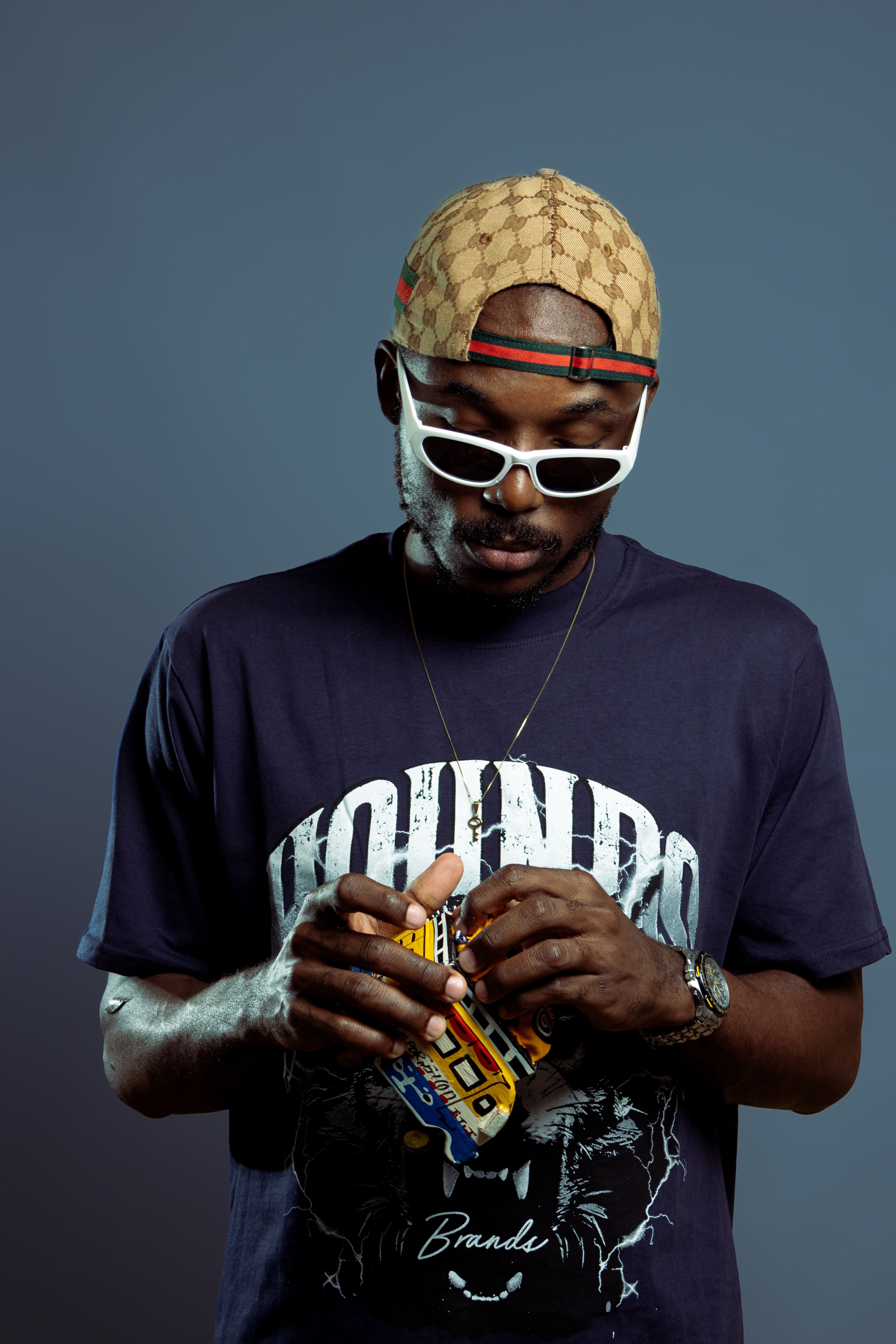 Portrait of a fashionable man in sunglasses and cap, Senegal setting.