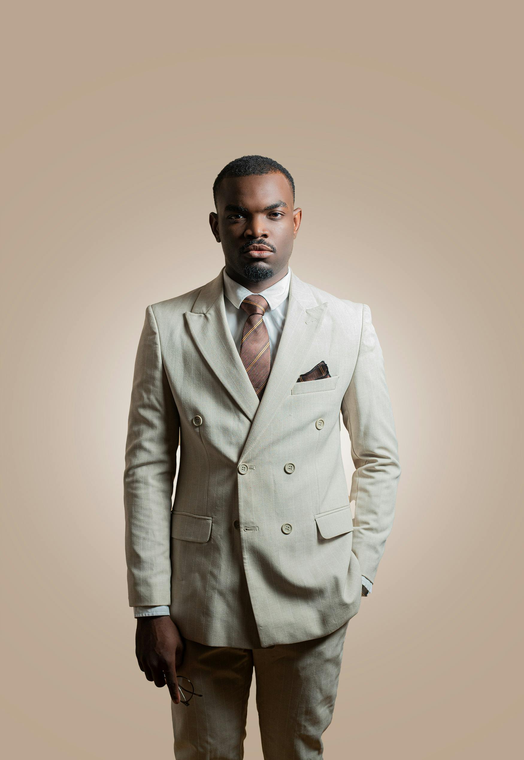 Miễn phí Chân dung một người đàn ông tự tin trong bộ vest màu nâu, cà vạt màu nâu và áo sơ mi trắng trên nền trung tính. Ảnh lưu trữ