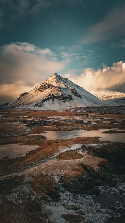 Free Breathtaking view of a snow-capped mountain and rugged terrain at sunset in Iceland, showcasing natural beauty. Stock Photo
