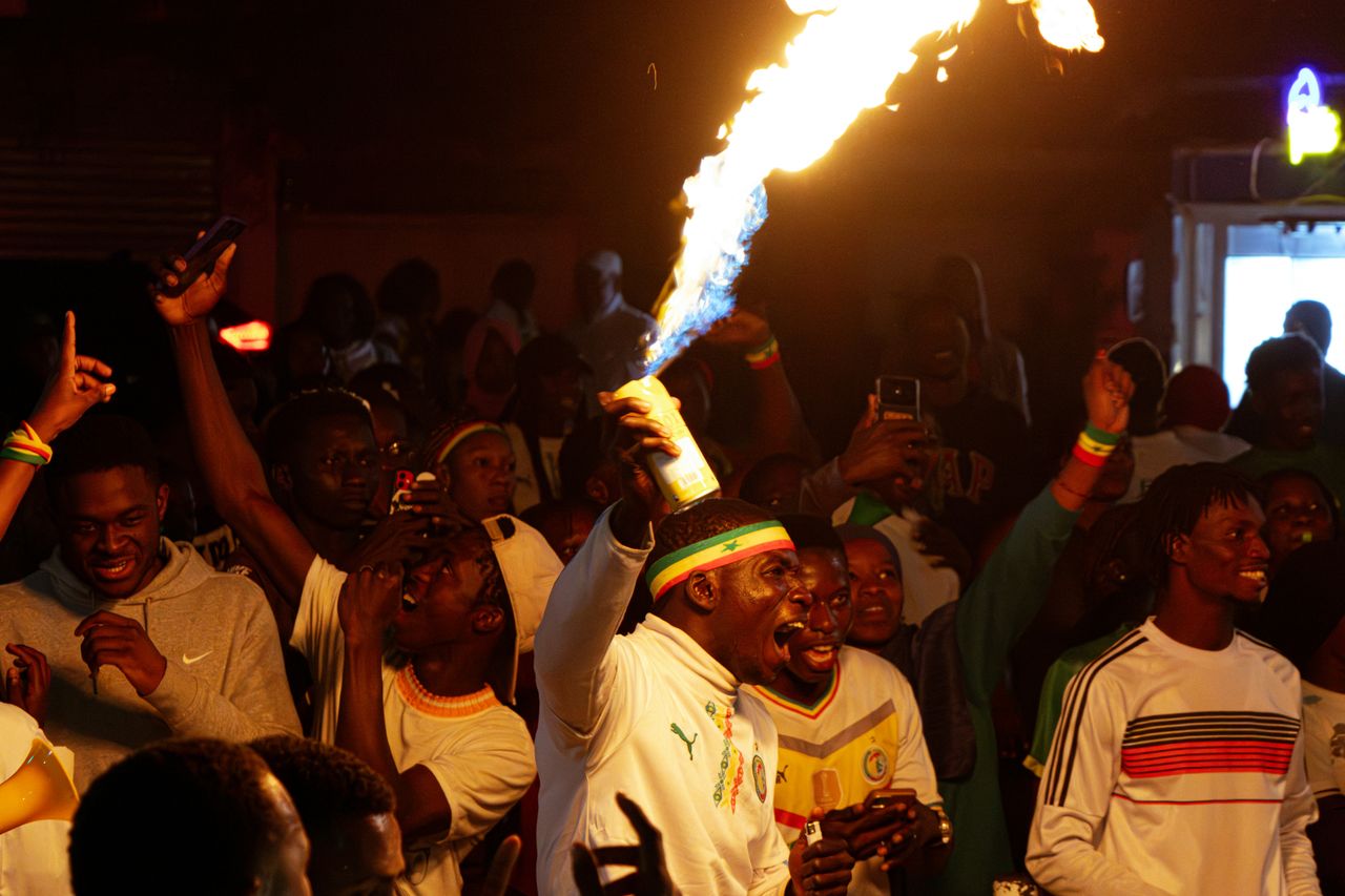 a lively night celebration in senegal with a man holding a firework as