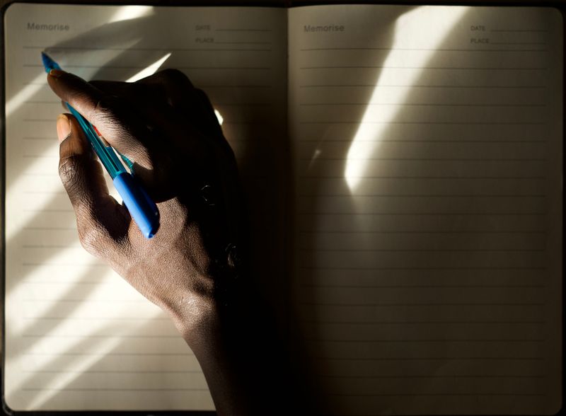 A hand writing in a journal, illuminated by soft natural light, creating elegant shadows.