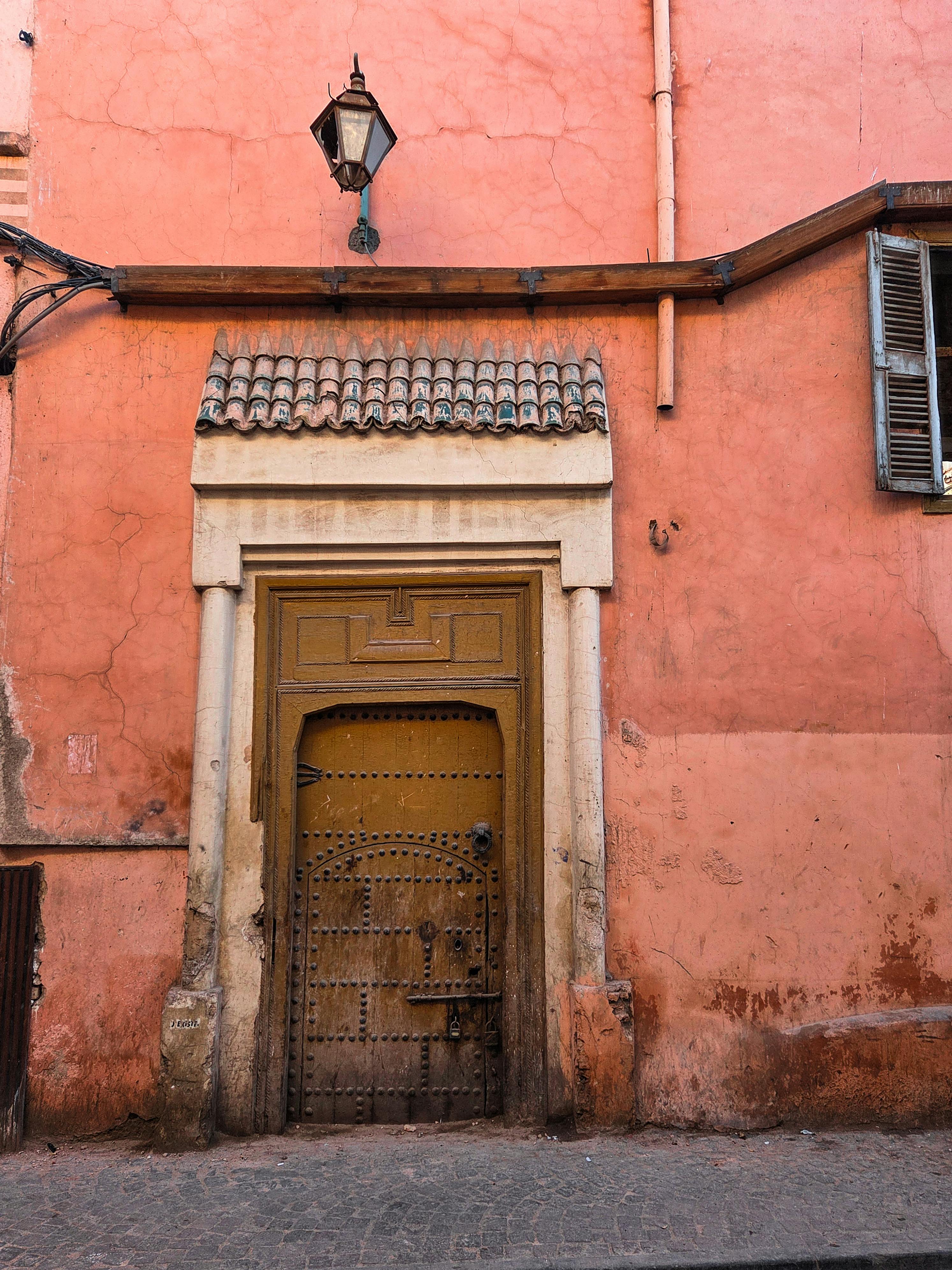bezplatná Rustikální dřevěné dveře zasazené do růžové zdi v Marrákeši v Maroku, představující místní architekturu. Základová fotografie
