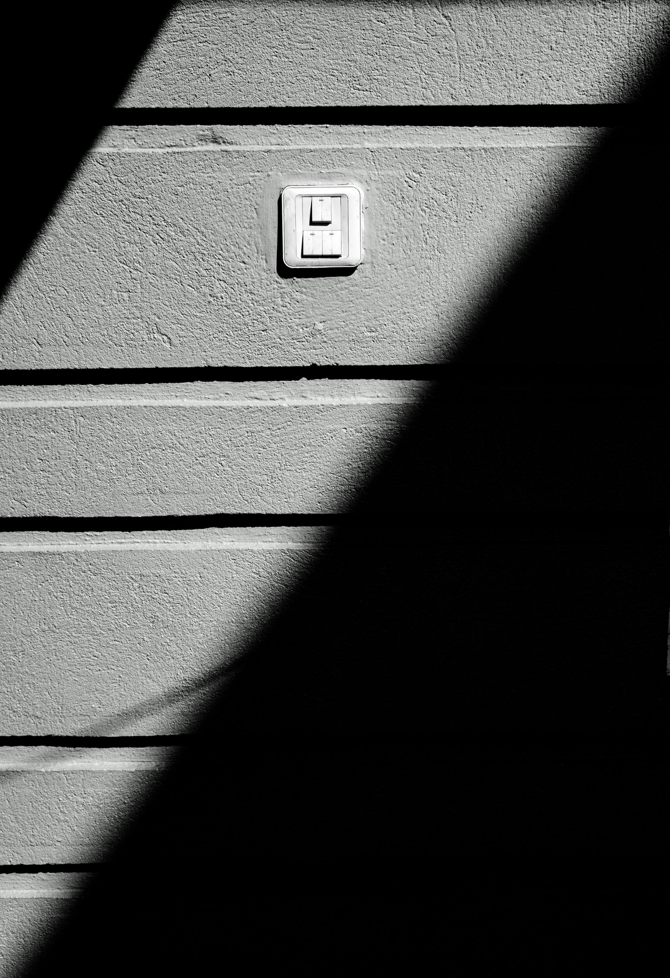 ingyenes Egy fekete-fehér absztrakt kép, amely egy csíkos falon lévő villanykapcsolót emel ki. Stockfotó