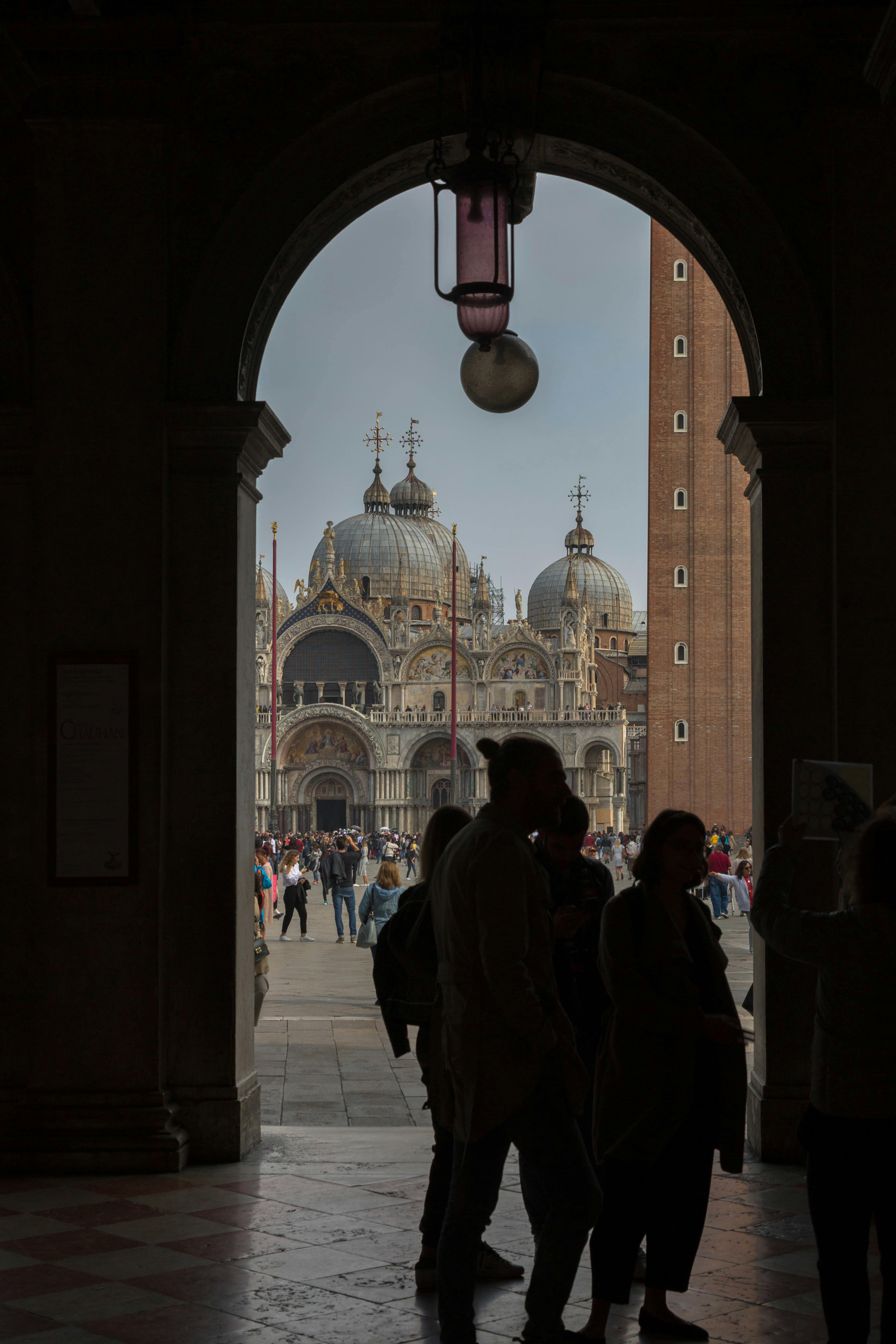 bezplatná Silueta lidí pod obloukem s bazilikou svatého Marka v pozadí. Základová fotografie